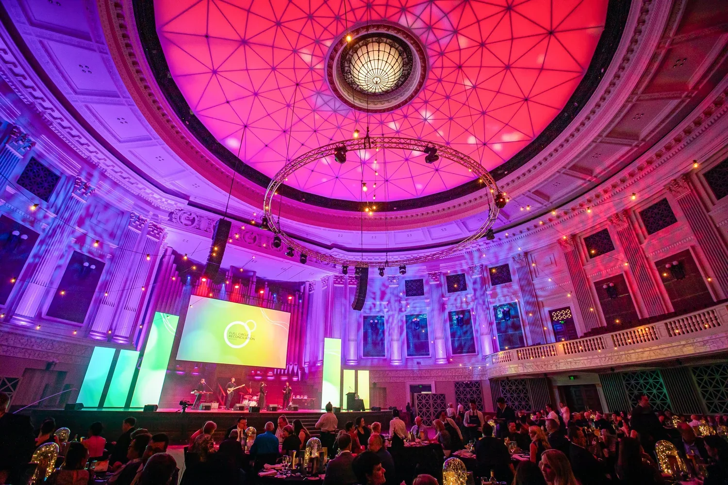 Corporate gala dinner and awards event at Brisbane City Hall with stage lighting and entertainment, and guests seated throughout the venue.
