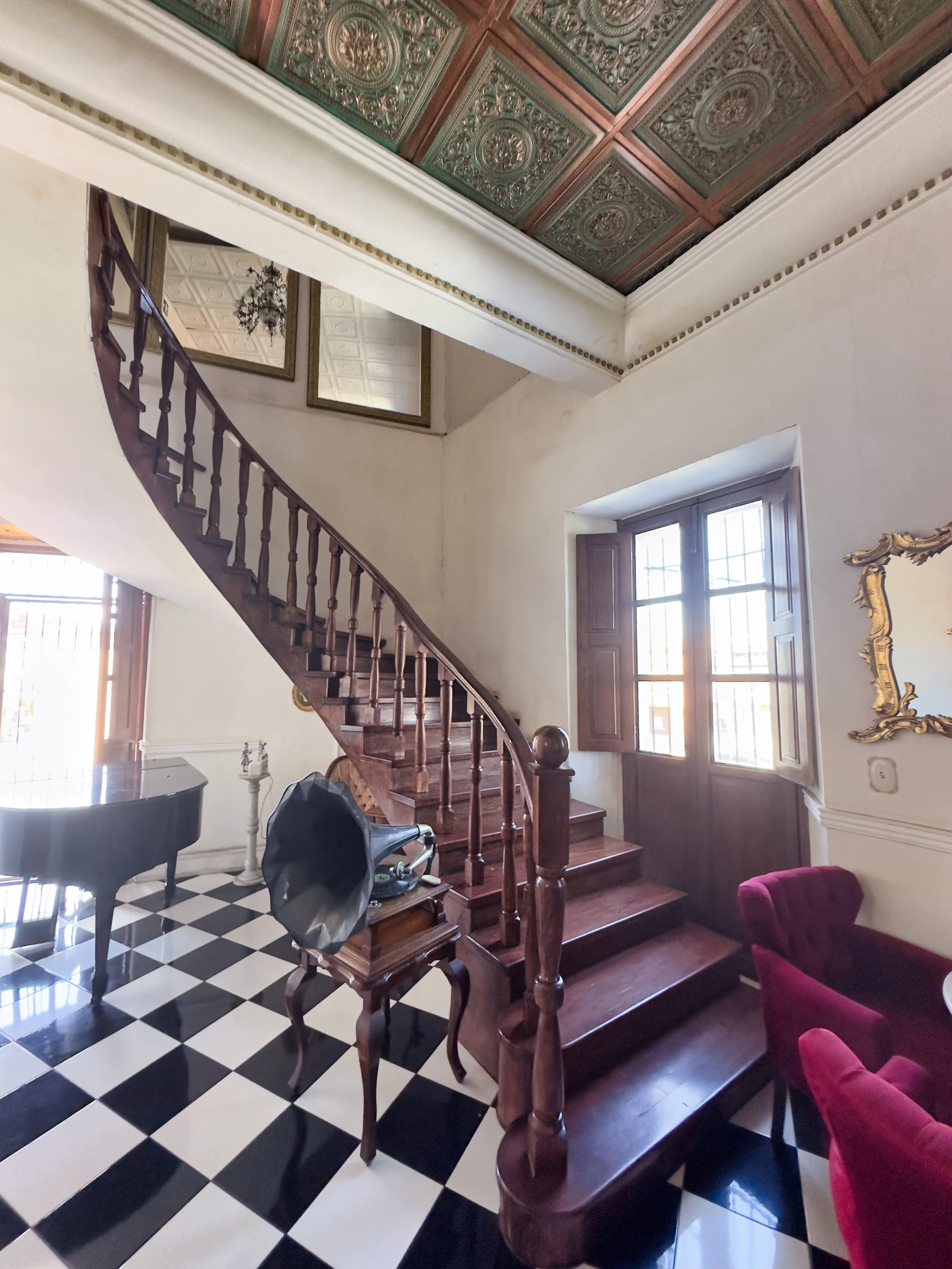 a grand piano, a gramophone and stairs leading to rooms