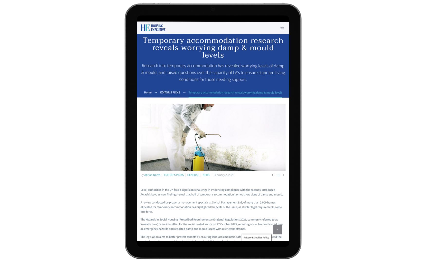 A tablet screen showing a webpage about temporary accommodation research revealing worrying damp and mold levels, with a photo of a person in protective clothing spraying mold off a wall.