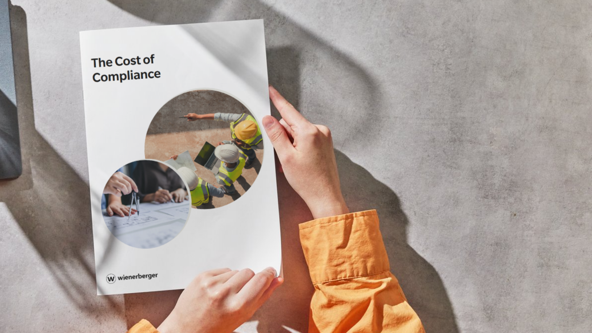 Hands about to turn the front page of a booklet with the title "The Cost of Compliance"