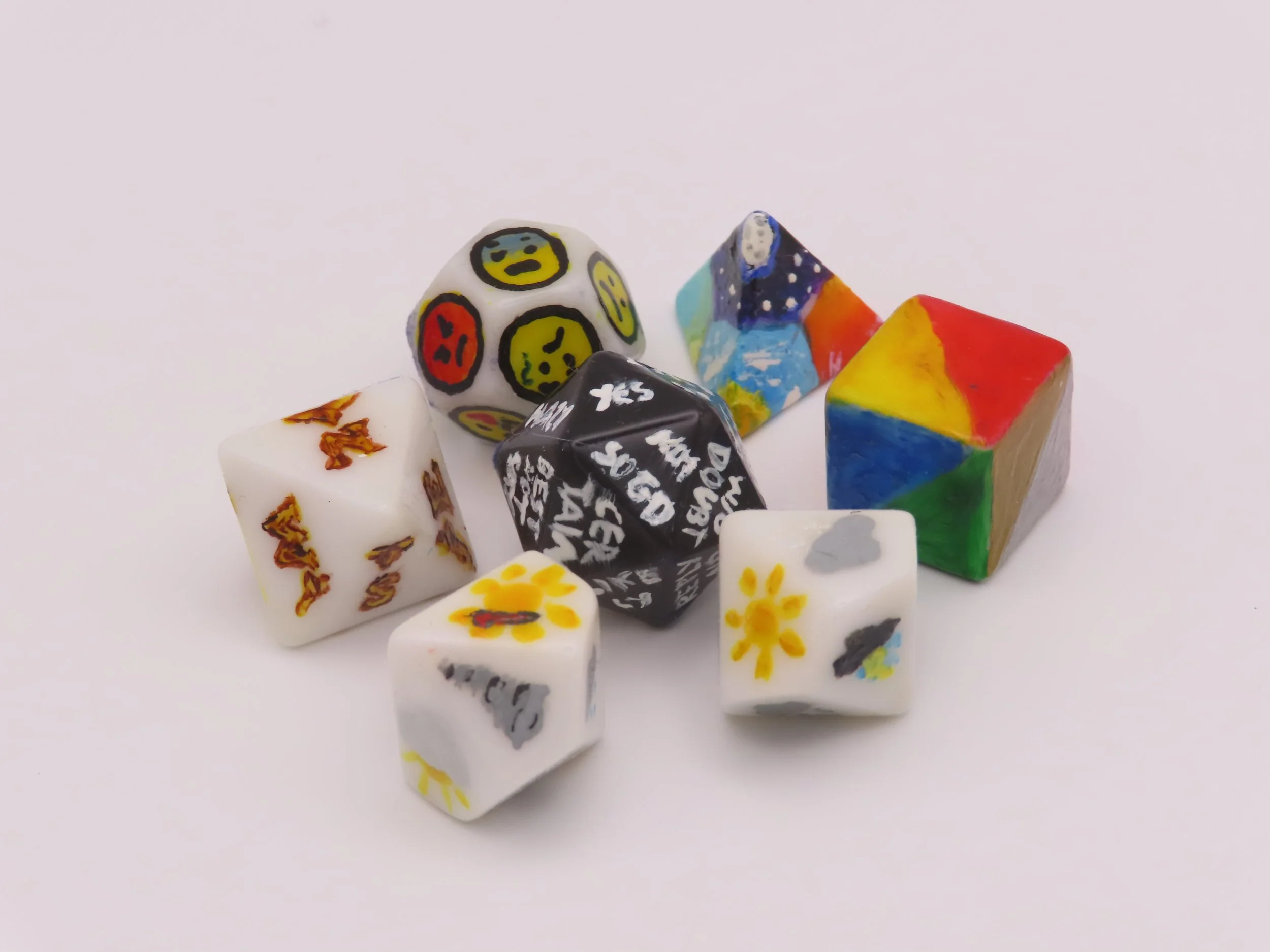 A set of dice of various shapes, with faces showing various words, colours and symbols