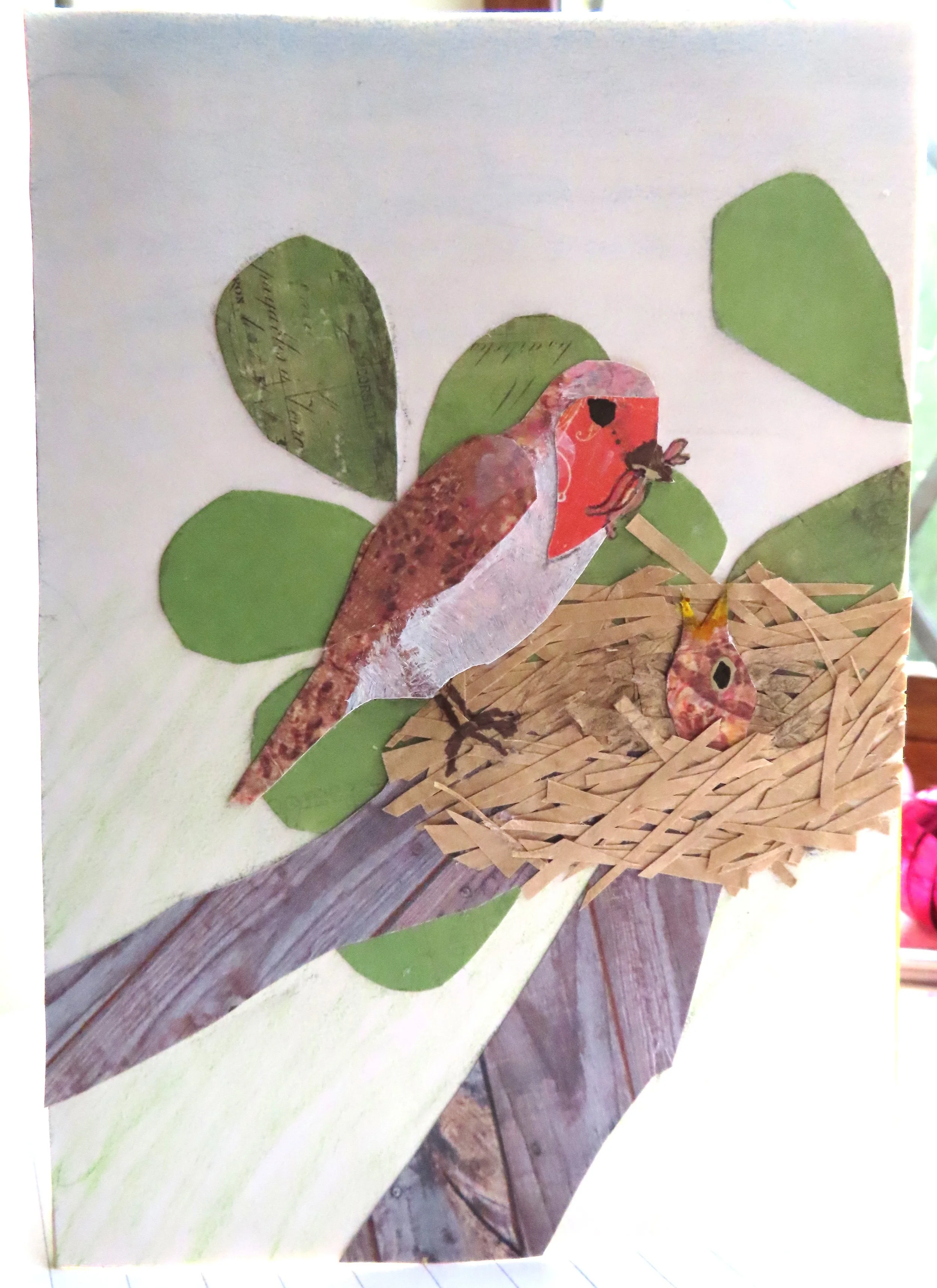 A handmade card depicting a robin feeding a chick in a nest