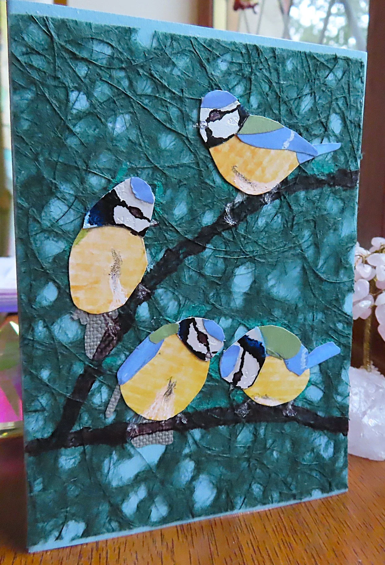 A handmade card depicting four blue tits on a branch