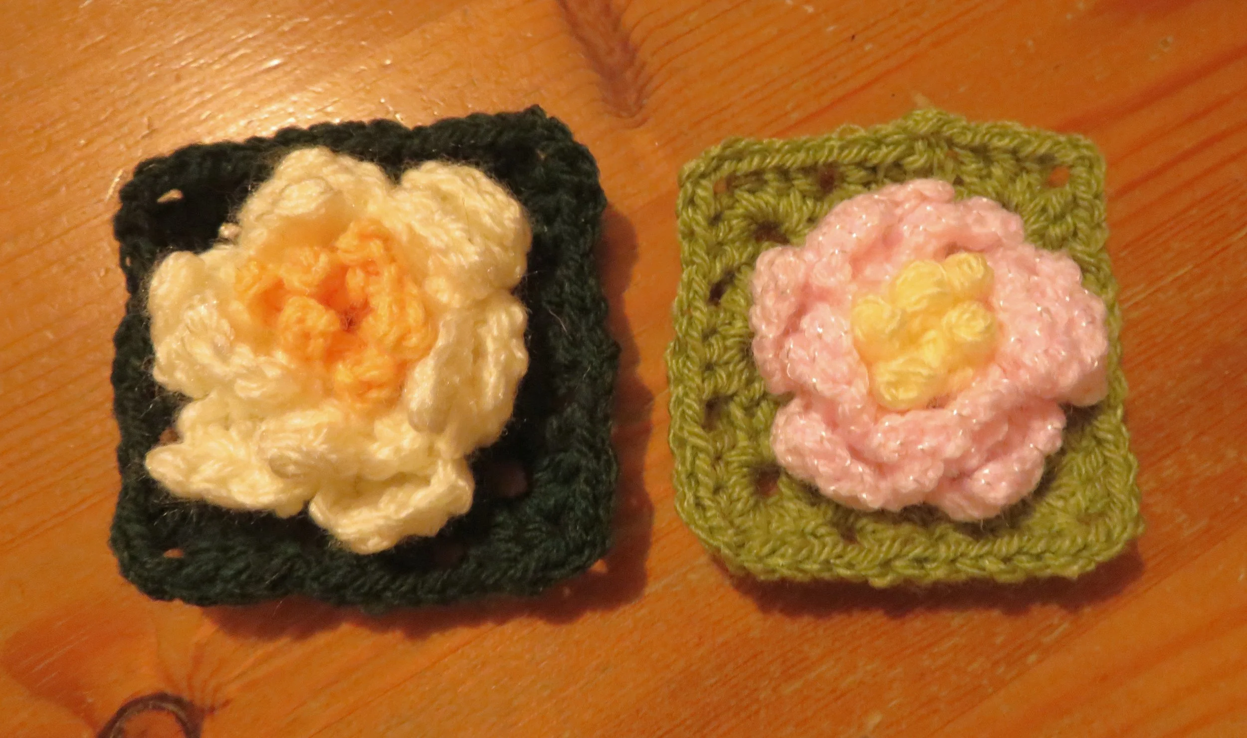Two crocheted water lilies on green crocheted squares