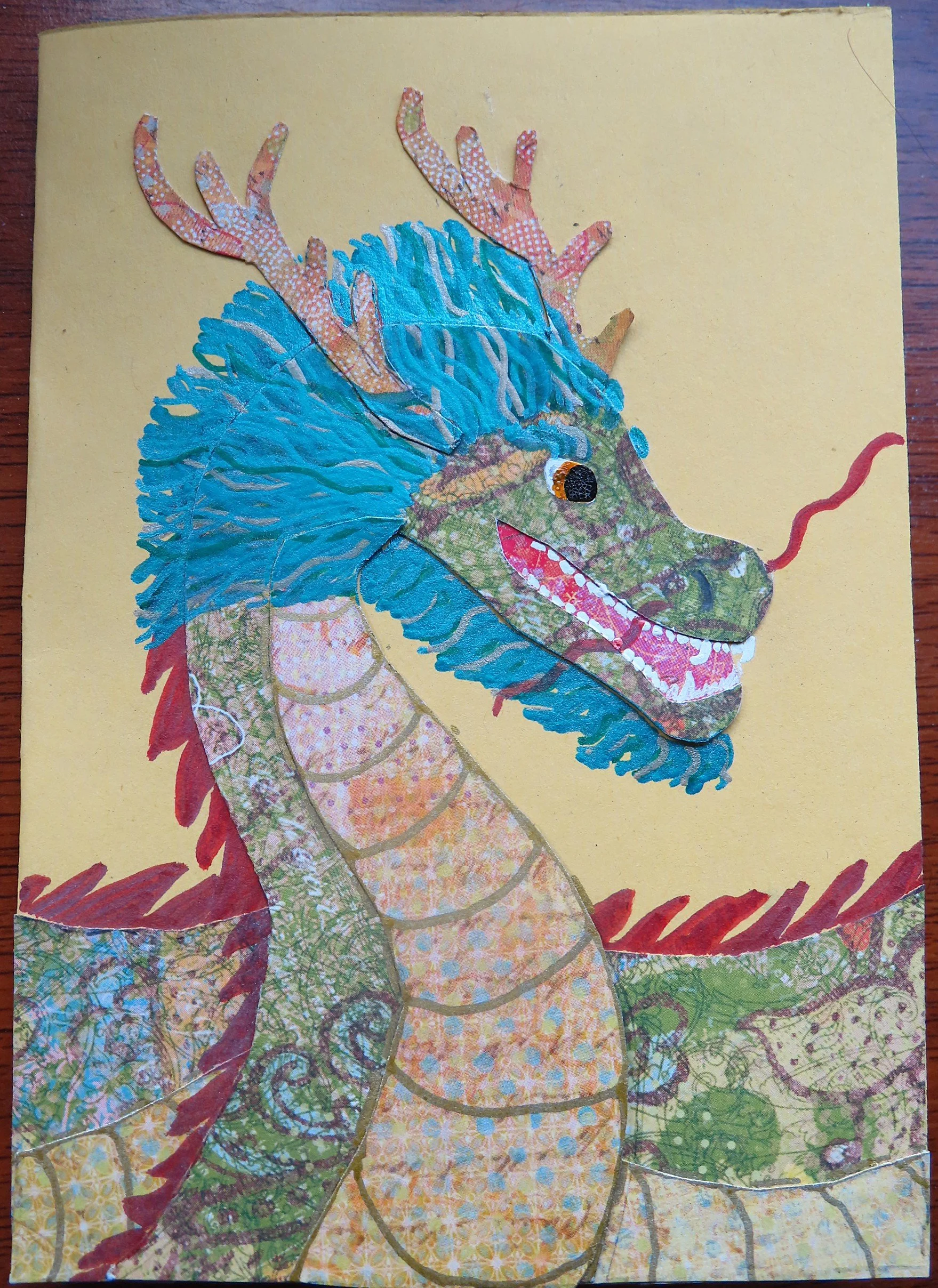 A handmade card depicting a green Chinese dragon with a yellow belly, red spines, orange antlers and blue mane