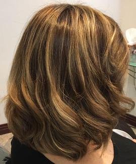 Woman with shoulder-length wavy hair in shades of light brown and blonde