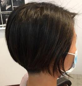 Side view of a woman with a short, layered bob haircut wearing a face mask.