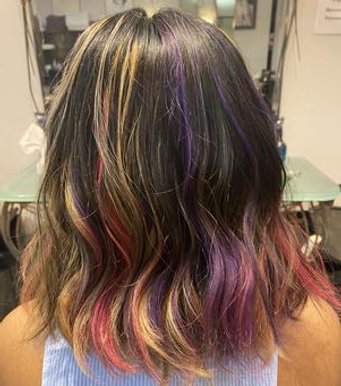 Back of a woman's head showing shoulder-length hair with multicolored highlights in shades of purple, pink, yellow, and orange.