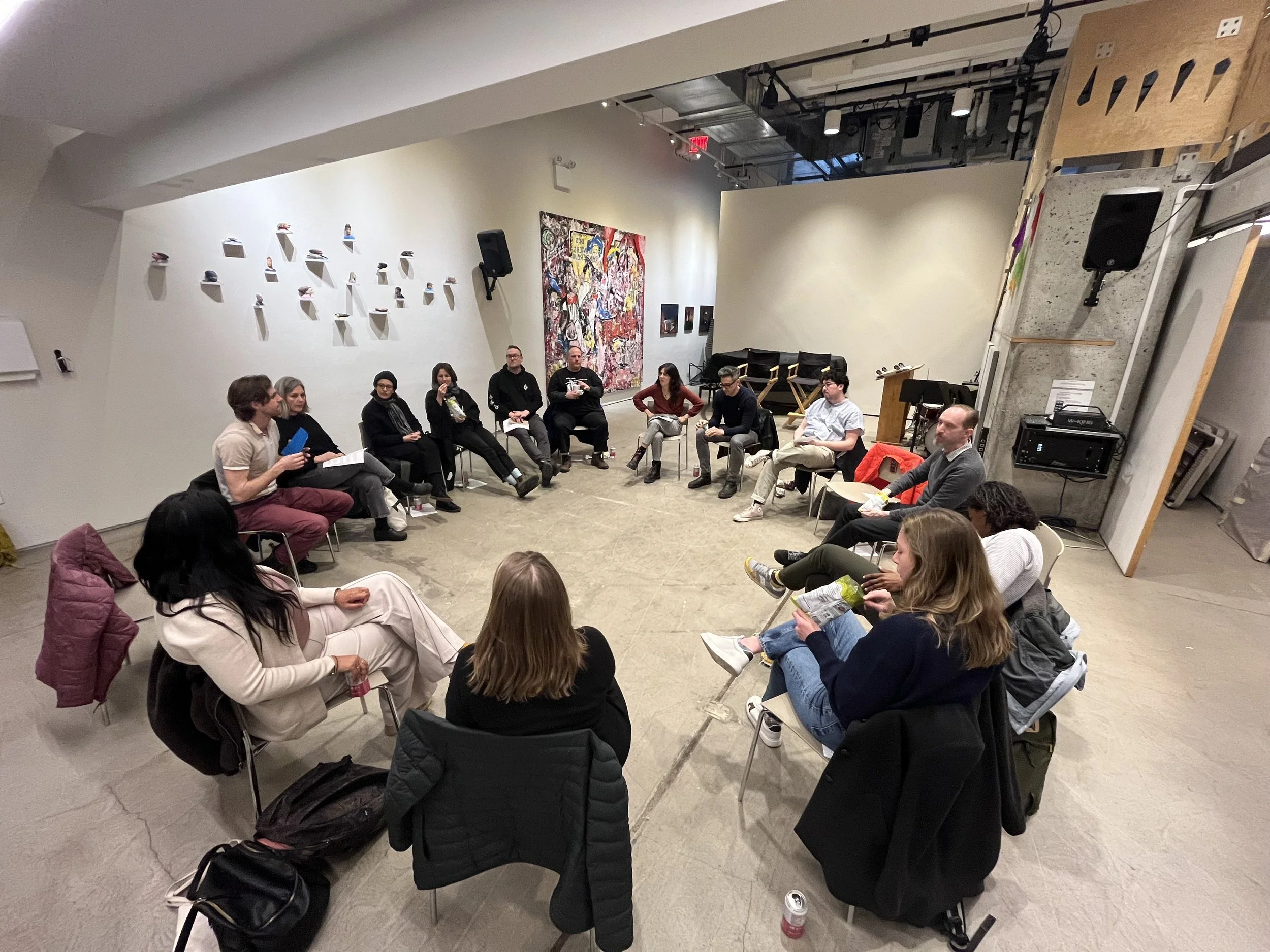 Group discussion in a modern art gallery with people seated in a circle.