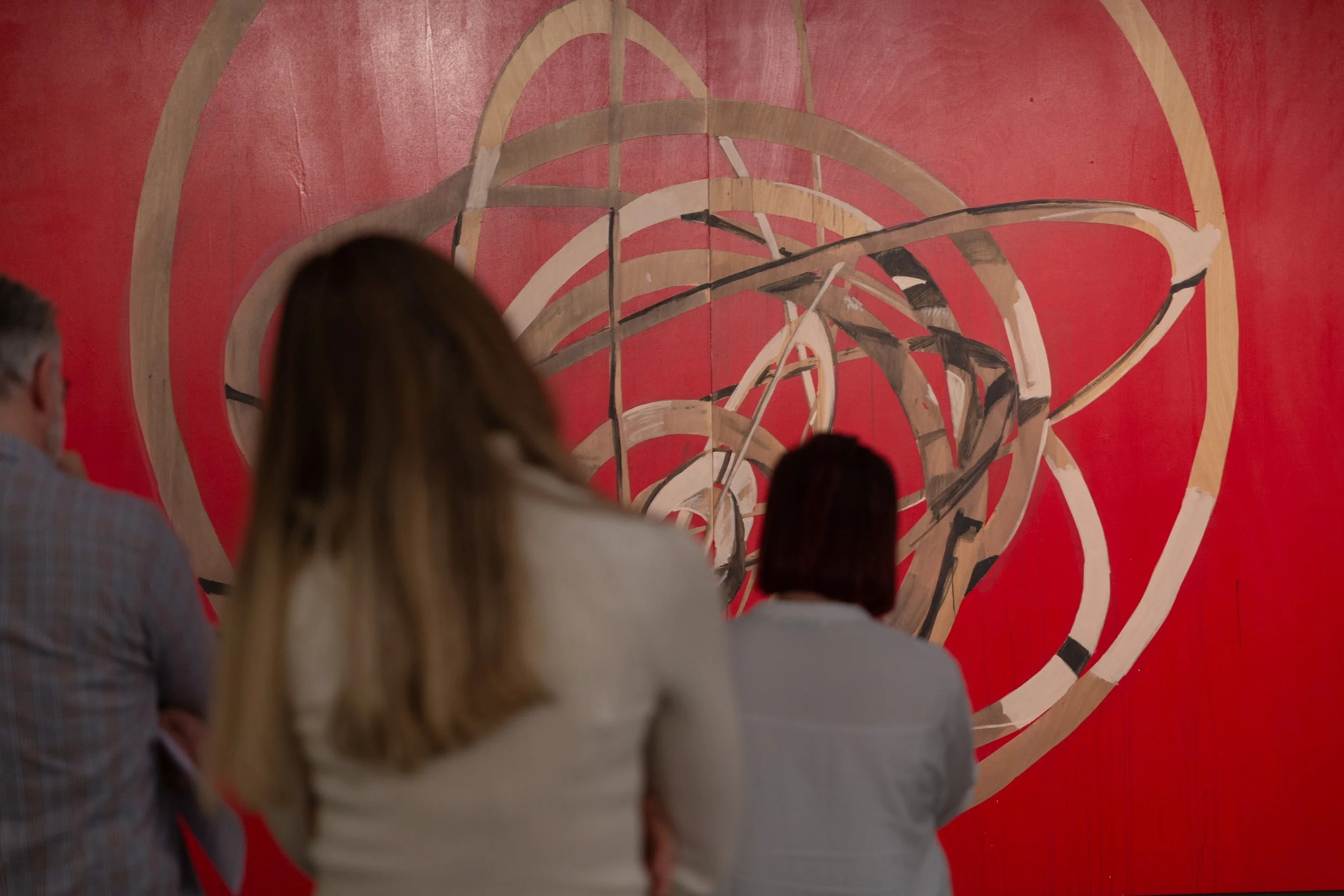 People viewing abstract art on a red background