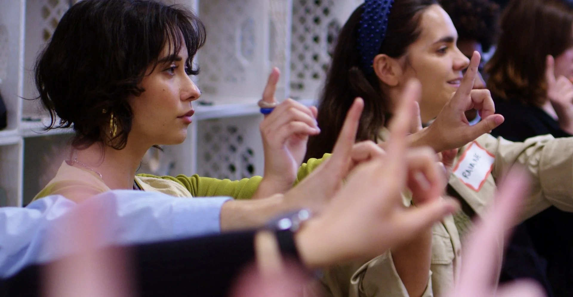 People holding fingers up in a classroom setting, possibly participating in an activity or lesson.