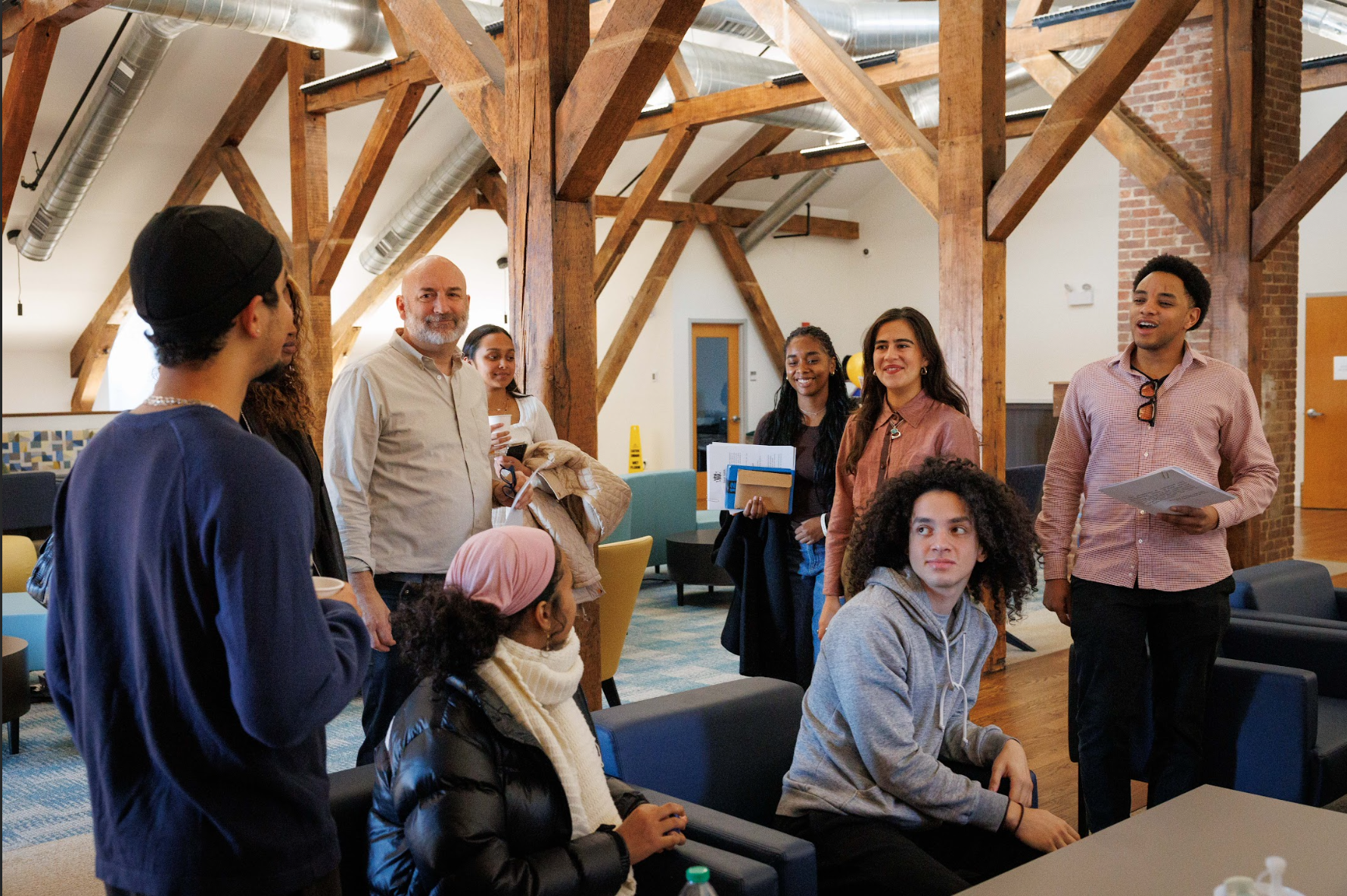 Group of people socializing inside a room with wooden beams.