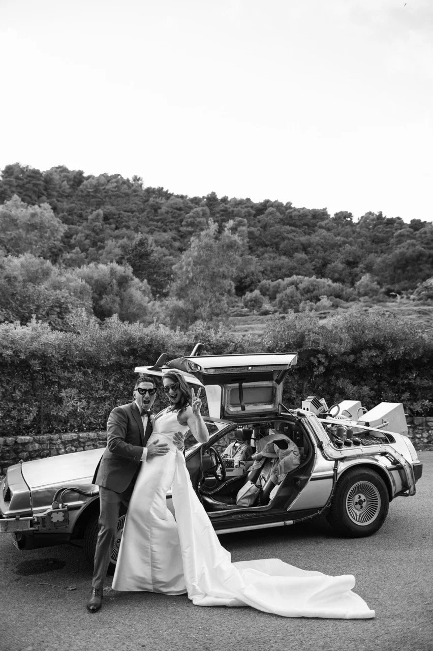 Un couple lors de leur mariage posant devant une voiture DeLorean à Saint Paul de Vence