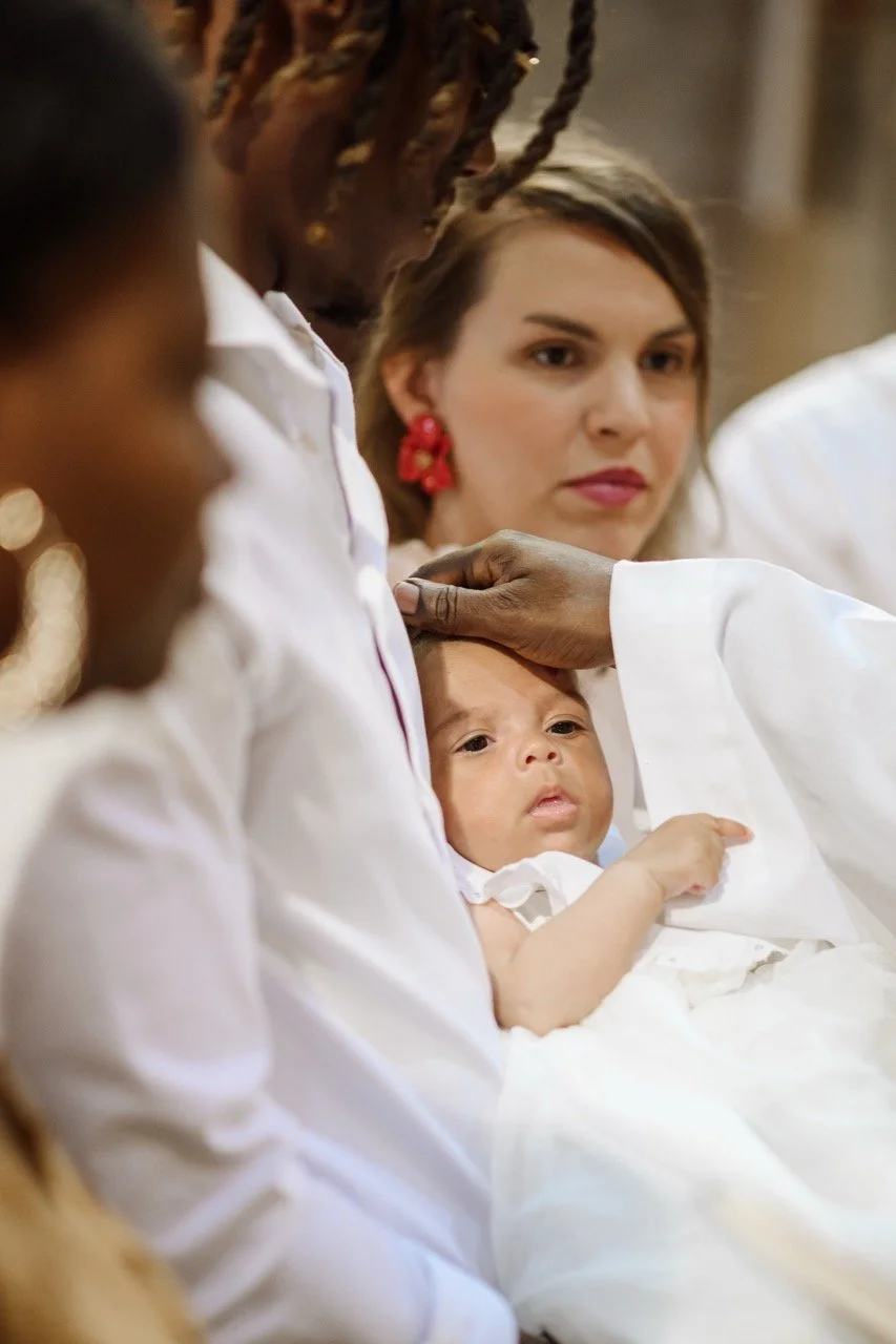 Une cérémonie religieuse avec plusieurs personnes habillées en blanc, dont une femme tenant un bébé pendant une cérémonie.