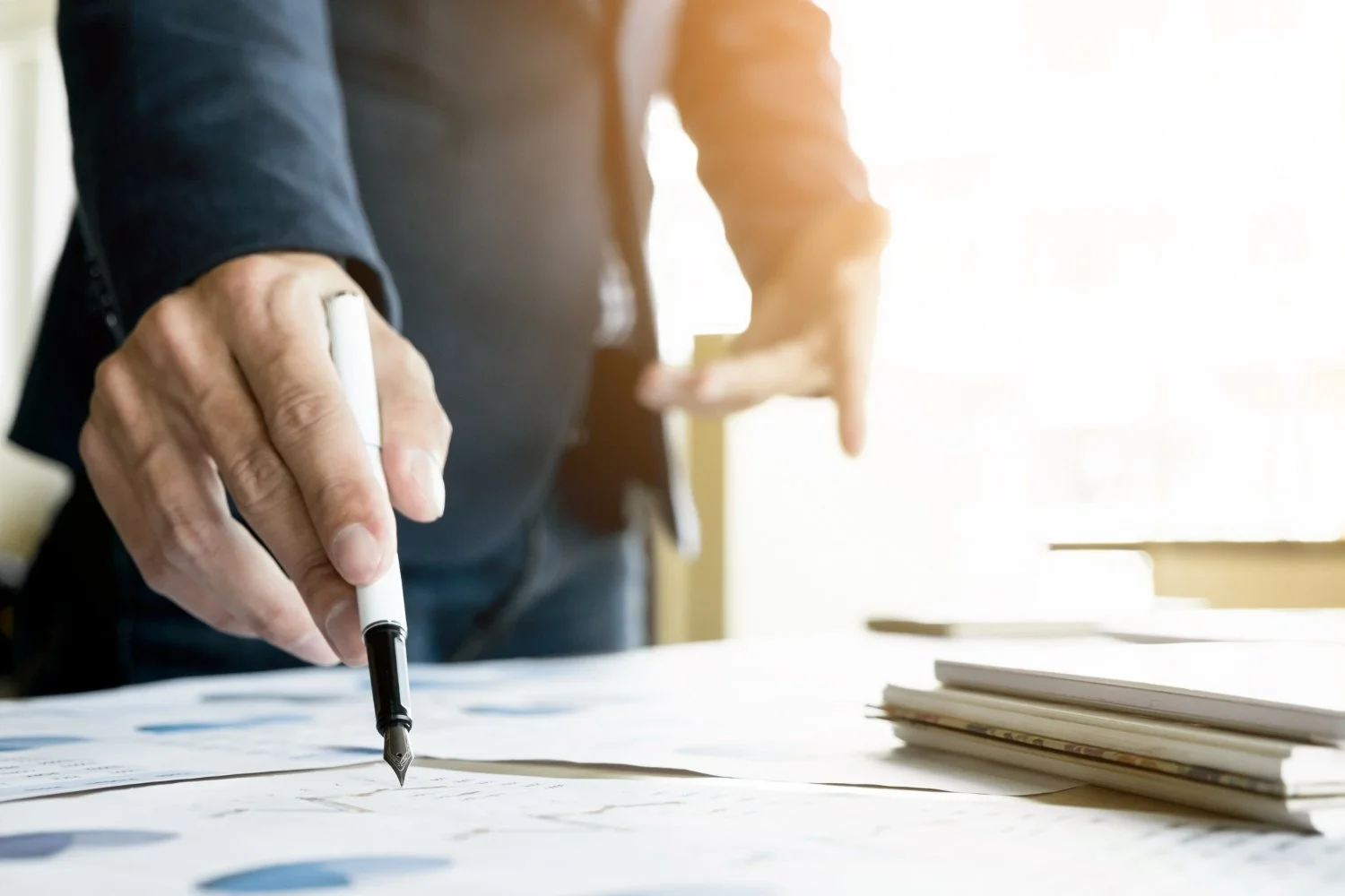 person-pointing-a-pen-at-paperwork-on-a-table.jpg