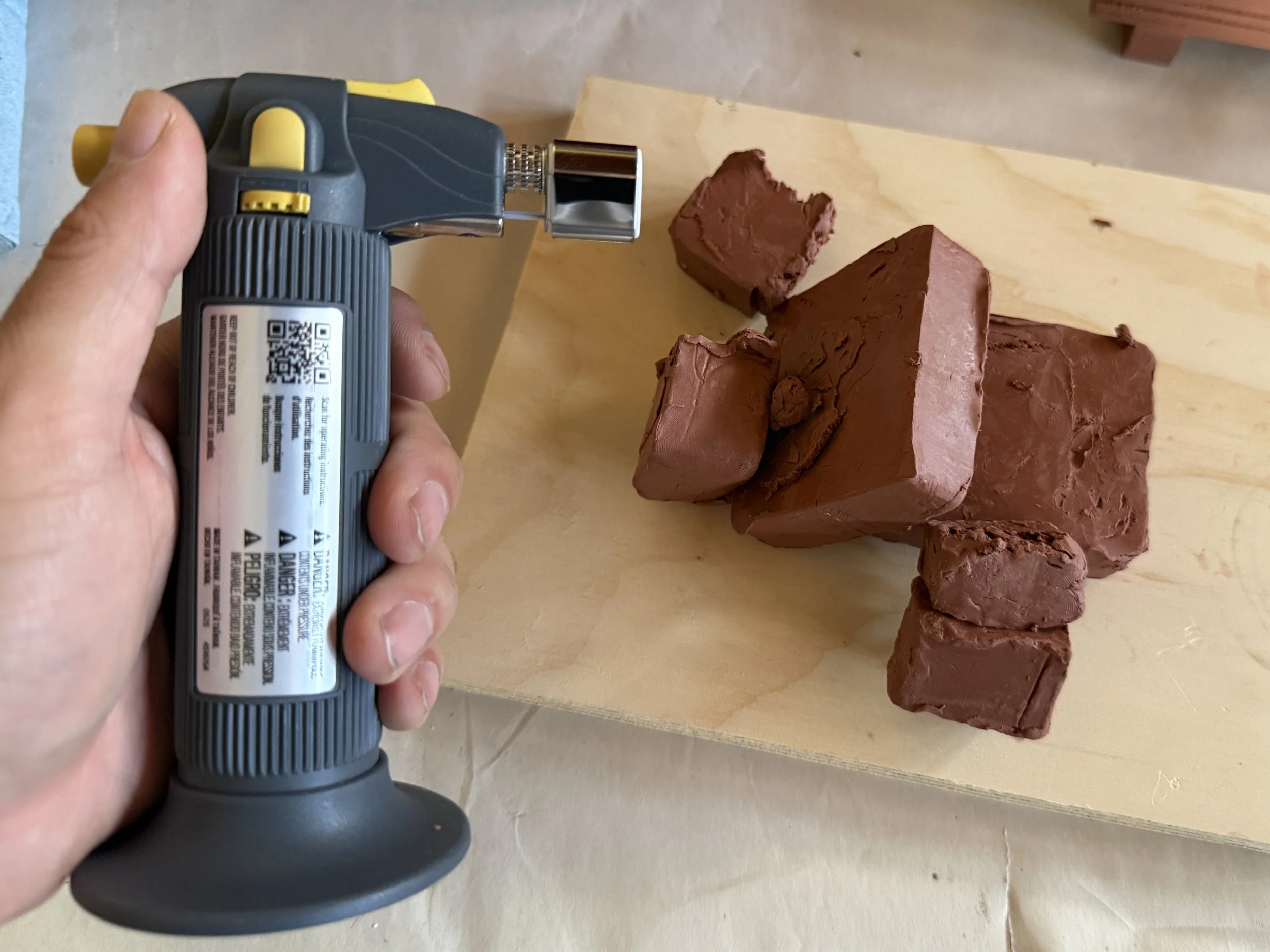 Butane torch being used to melt oil based clay