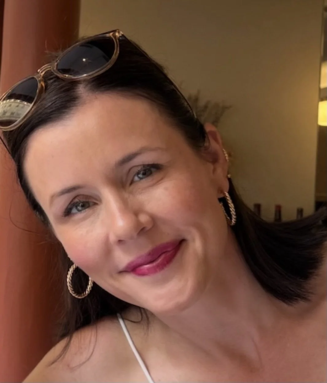 Smiling woman with brown hair and sunglasses on top of her head