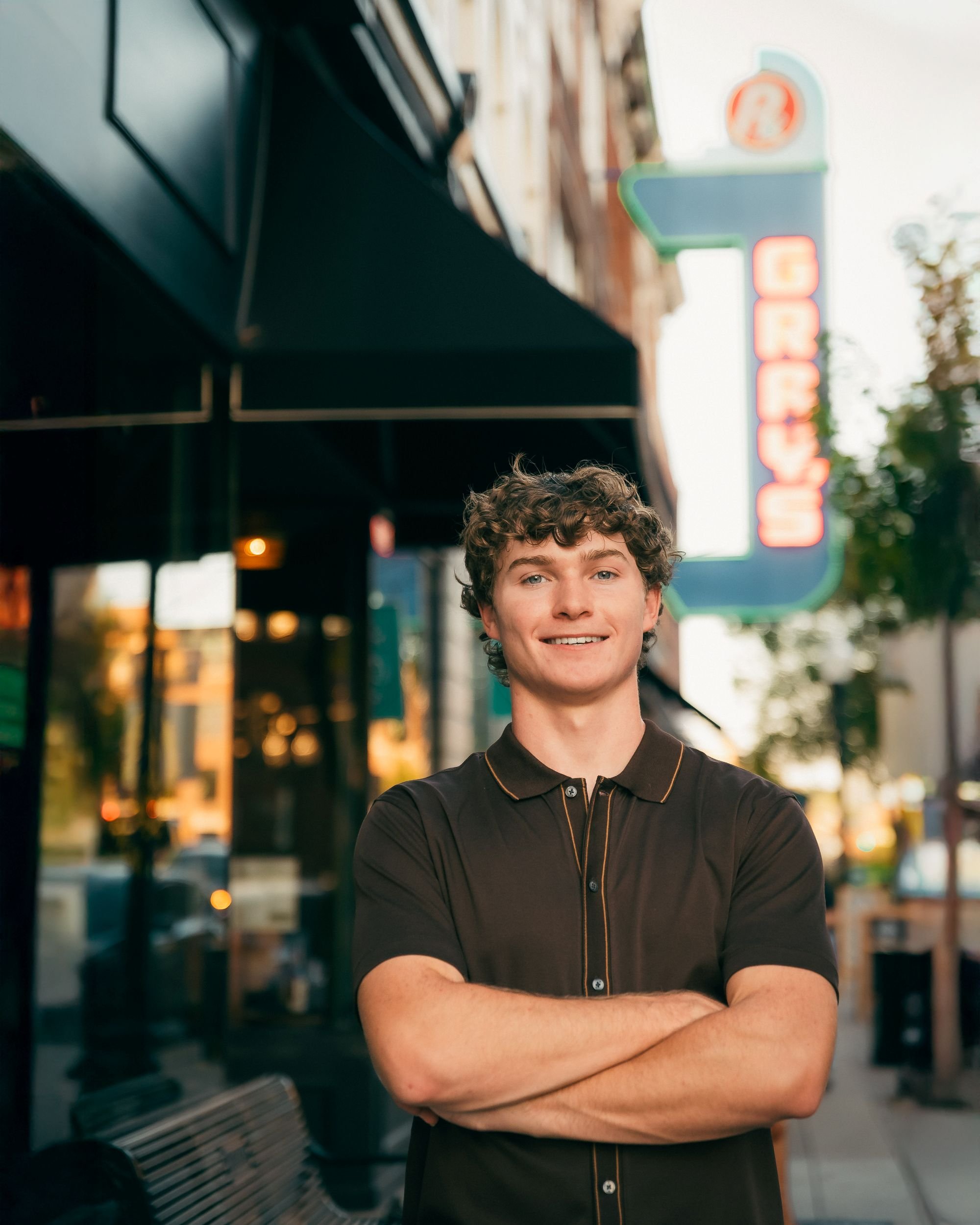 Young man in city scape with arms crossed.