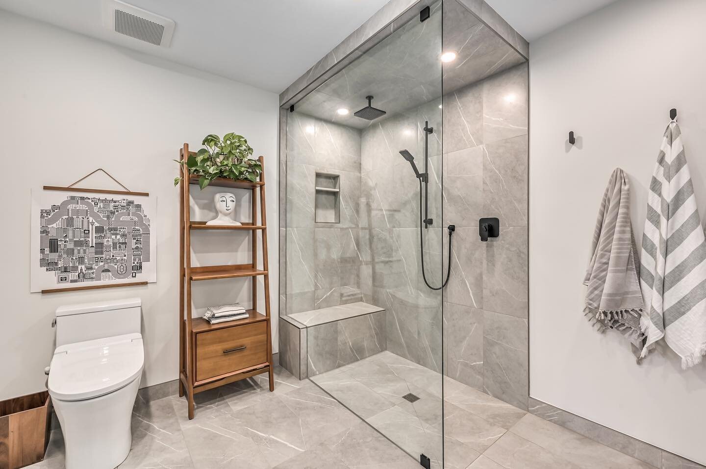 Clients wanted minimal glass and a clean sleek look. This open and curb-less shower features an envelope-cut base. This allows the use of large format tiles instead of mosaics when center drains cannot be changed into linear drains due to plumbing co