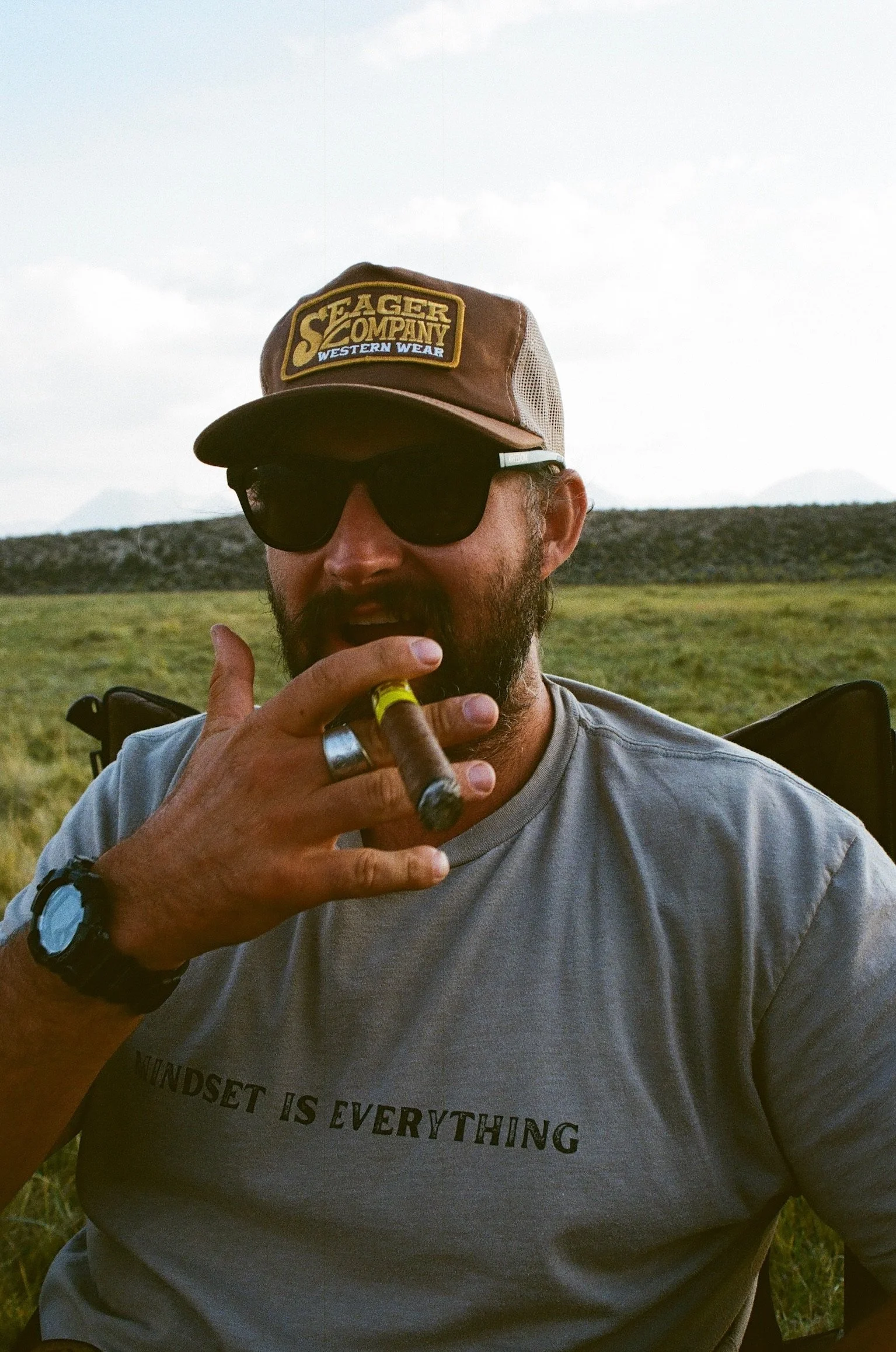 MAN IN HAT SMOKING A CIGAR WITH SUNGLASSES ON