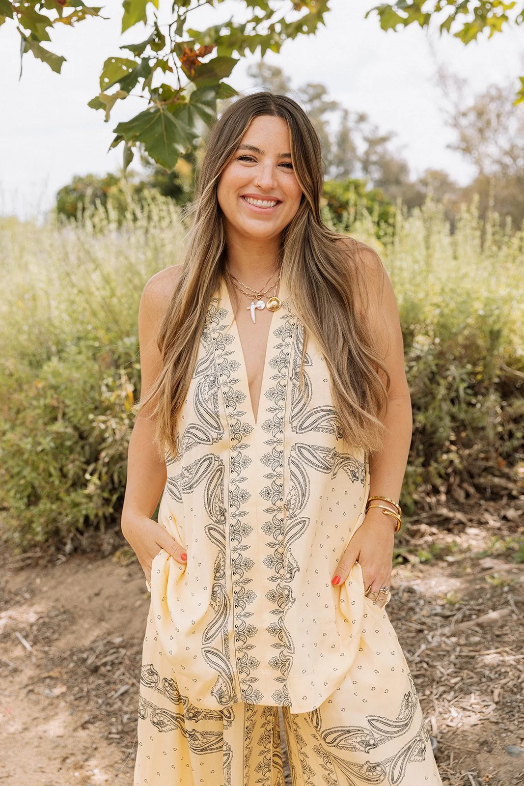 bree standing in a field of brush in a yellow set smiling at the camera