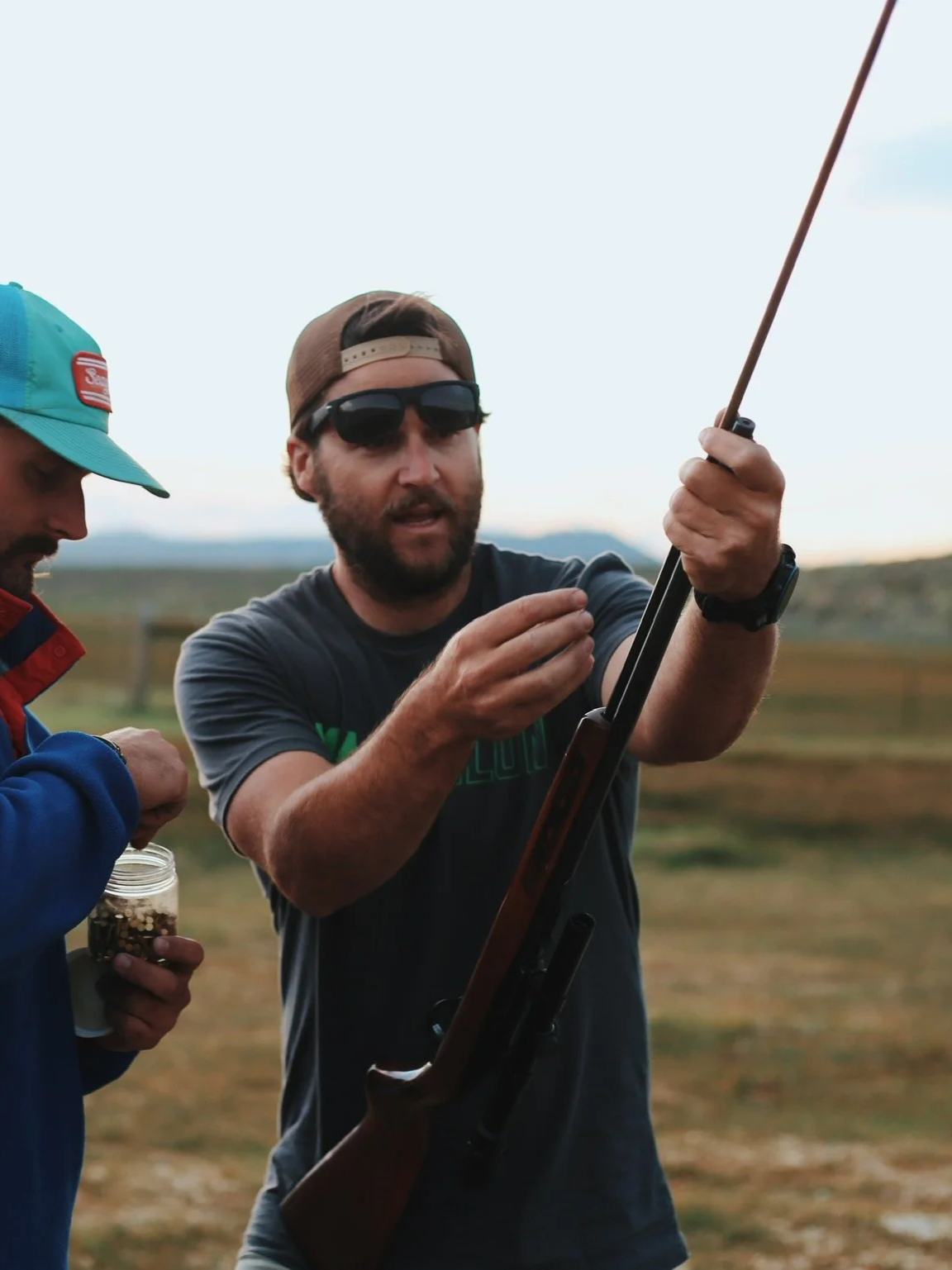 adam kakuska off the gryd leader loading a riffle while wearing sunglasses and backwards hat
