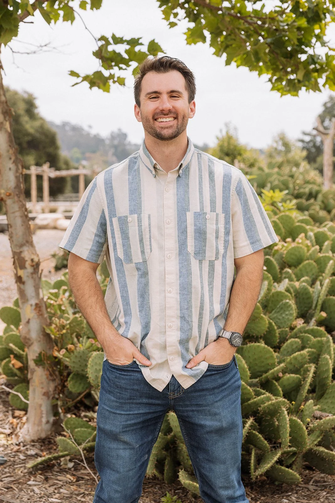 branden randall treasurer standing in a striped shirt by cactus smiling at the camera