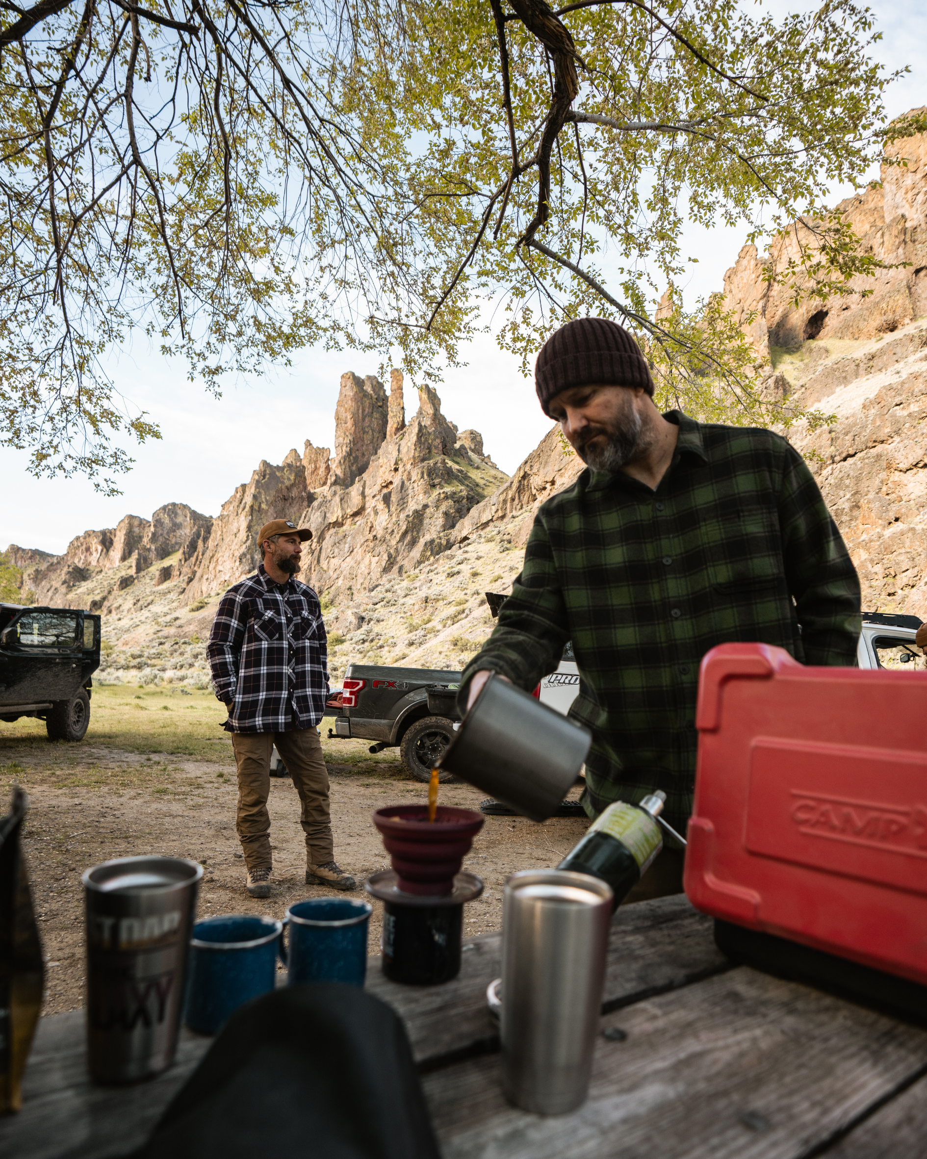 2 men at campsite making coffee under the rocky terrain mountains