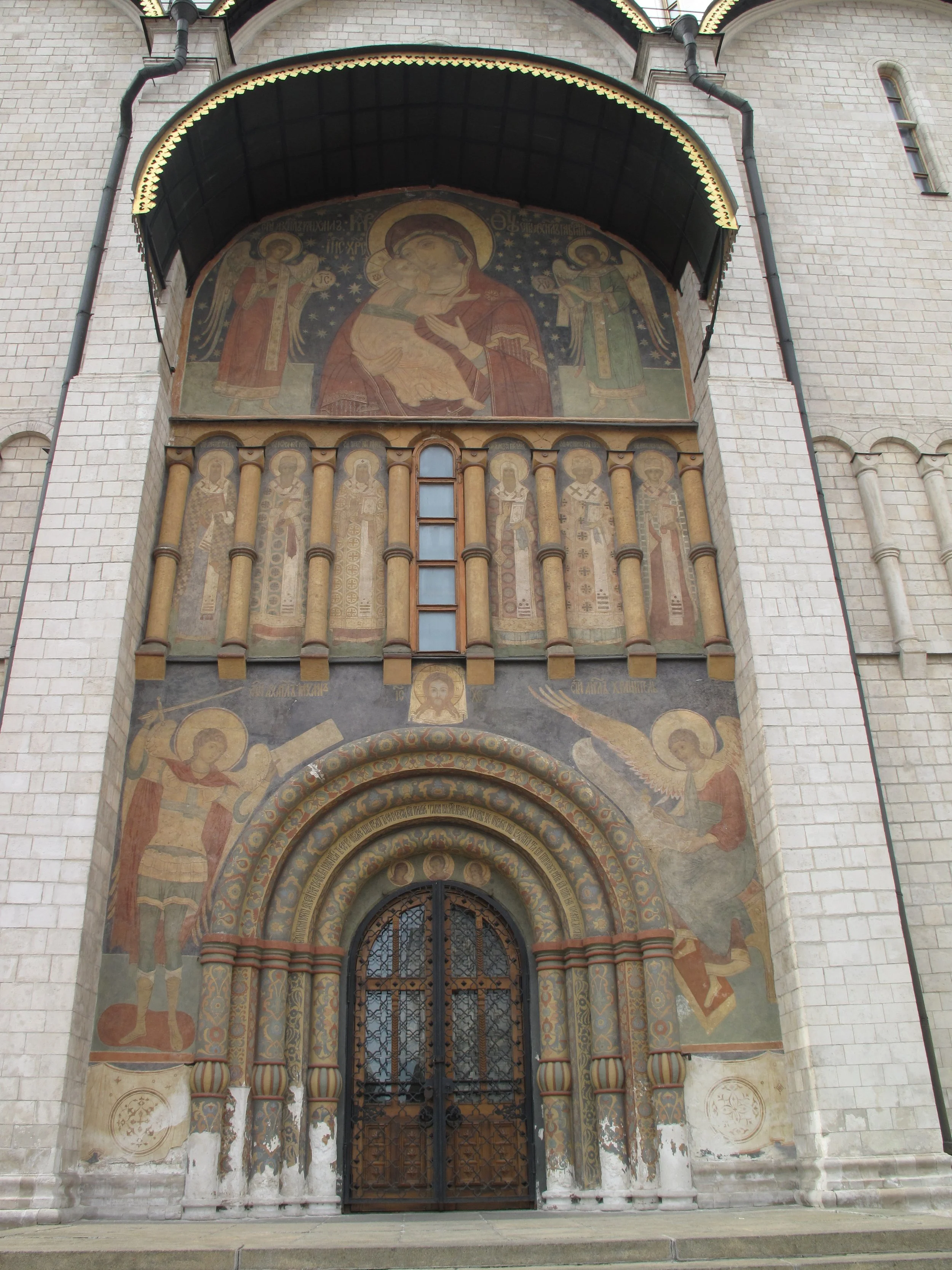 Exterior of a church with religious murals and a decorative gate at the entrance.