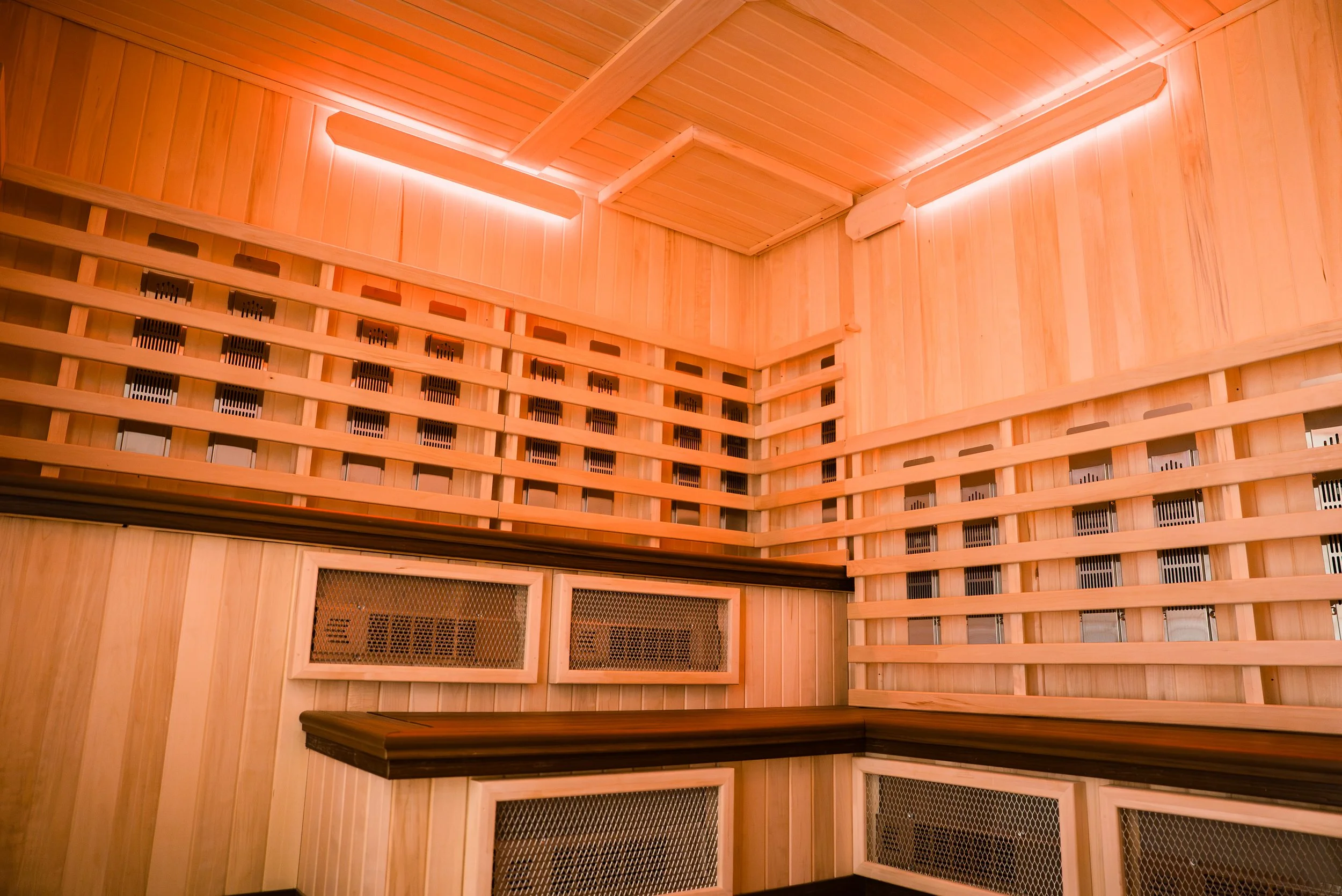 Interior of a sauna with wooden walls, ceiling, and benches, and LED lighting along the ceiling edges.