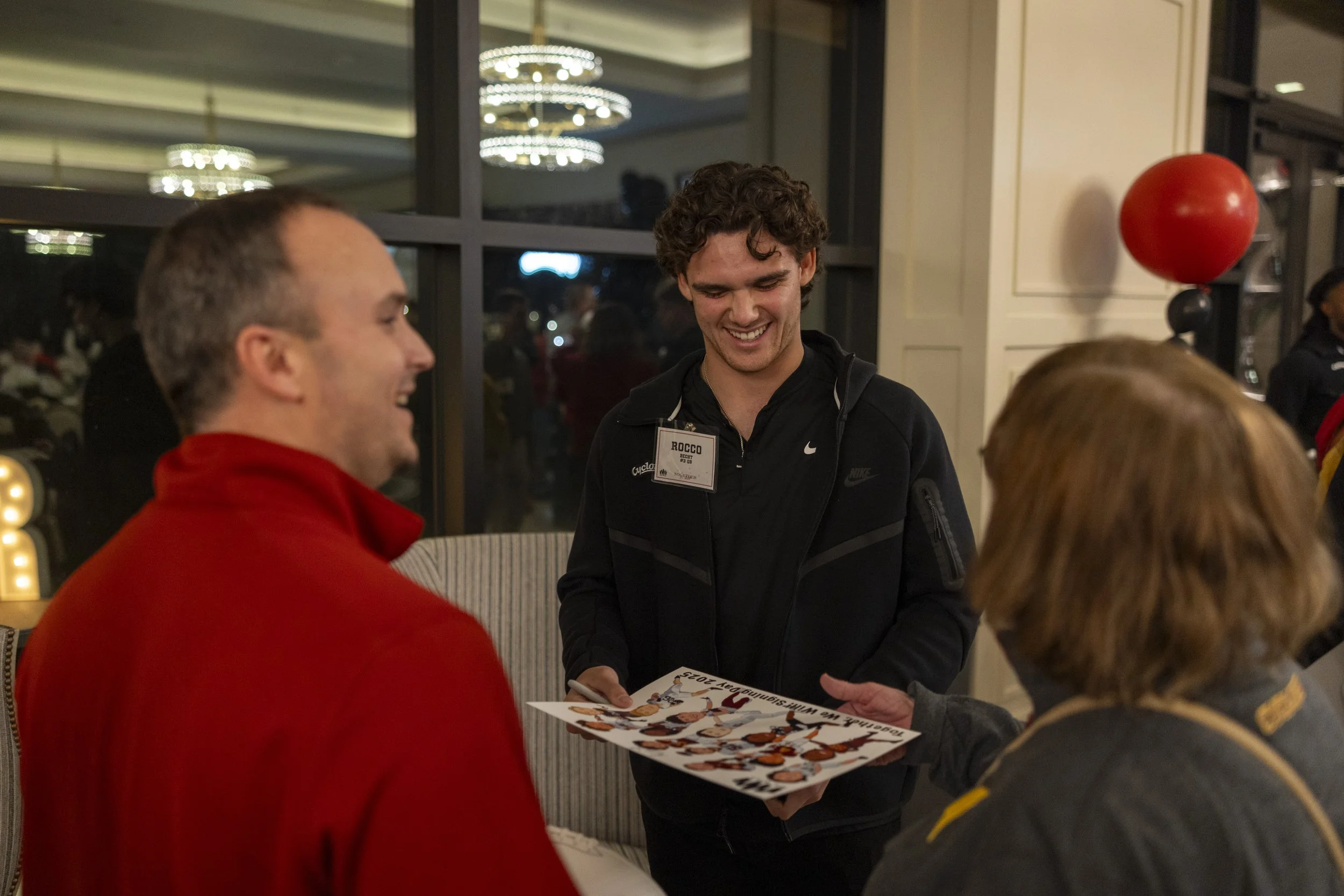 Group of people indoors at an event, one person holding a poster