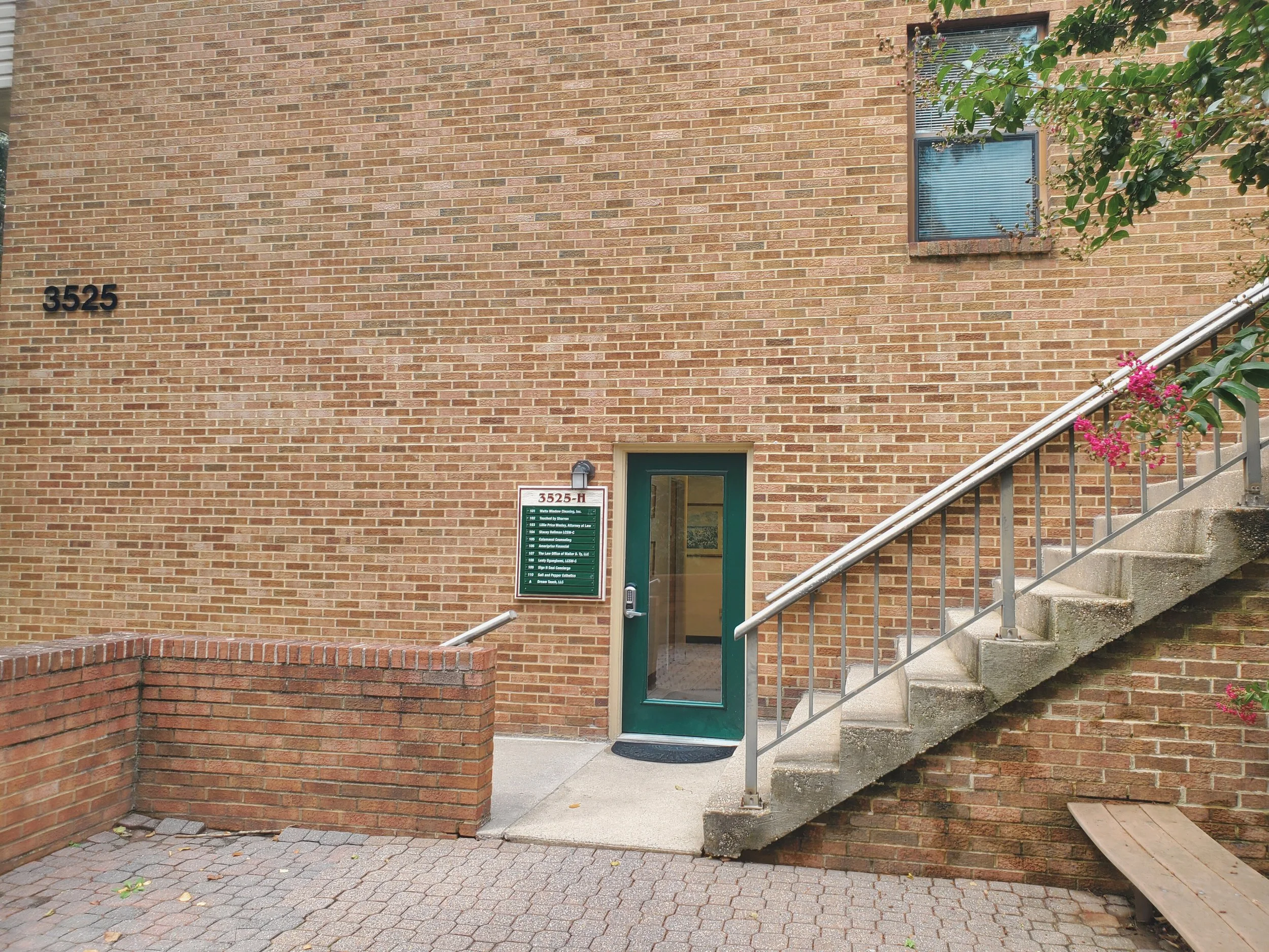 Outside of therapist office in Ellicott City, Maryland. Brick building with stairs and a glass door, a sign with office hours and building number 3525-H.