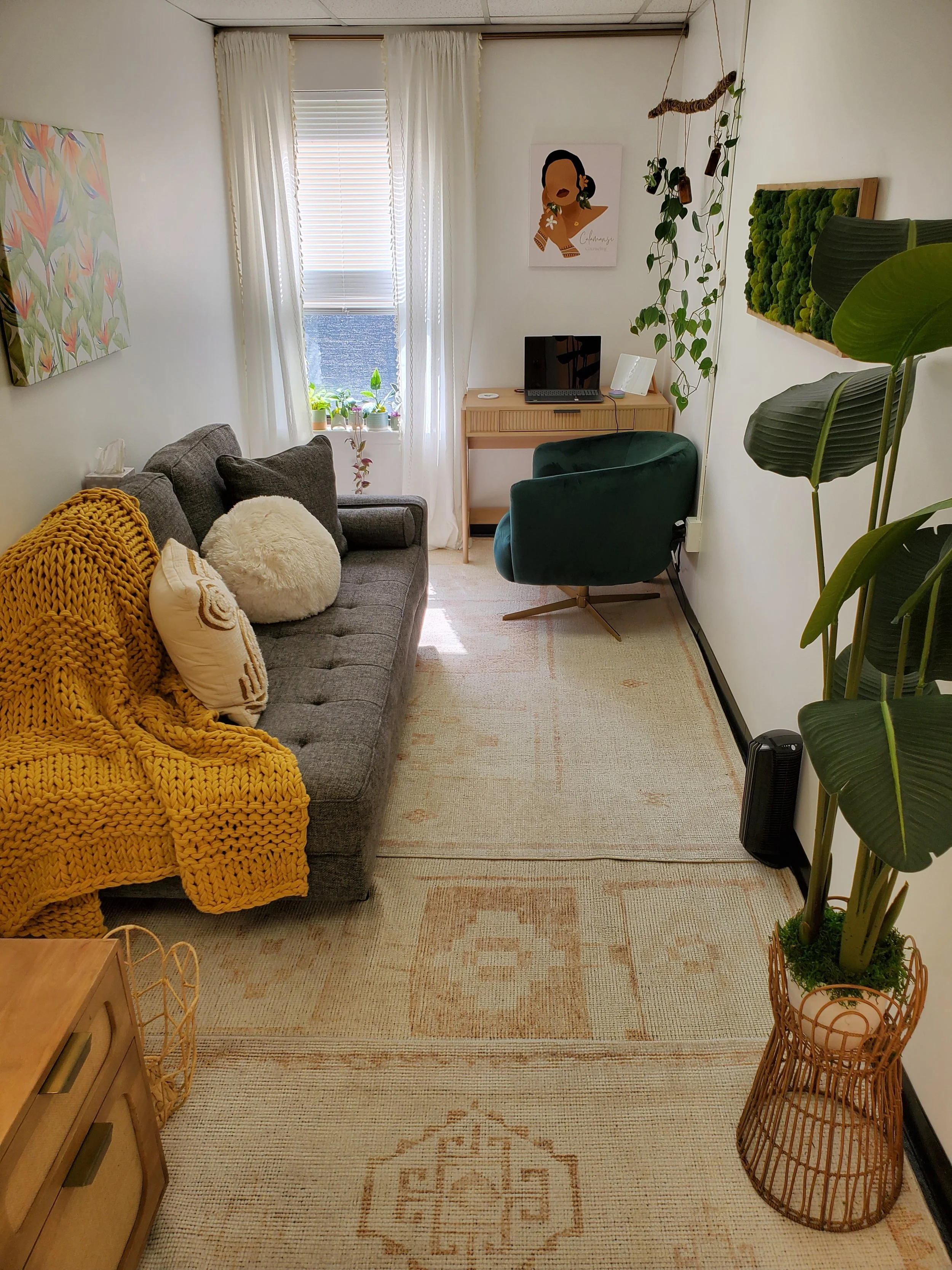 bright therapy office with grey couch, golden throw blanket with white pillows