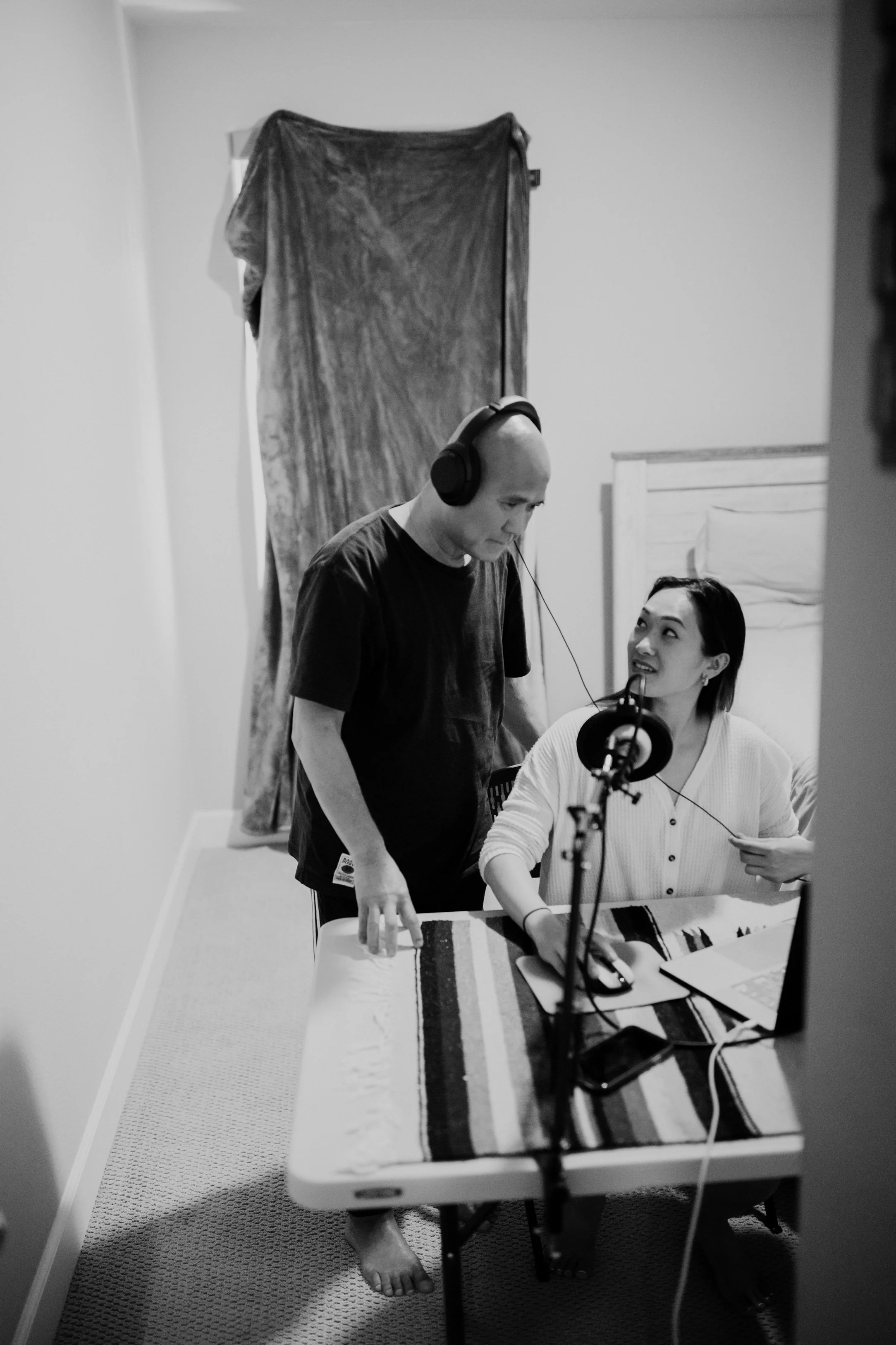 Robert Chau and Dorothy Chow looking at each other while recording their podcast Death in Cambodia, Life in America