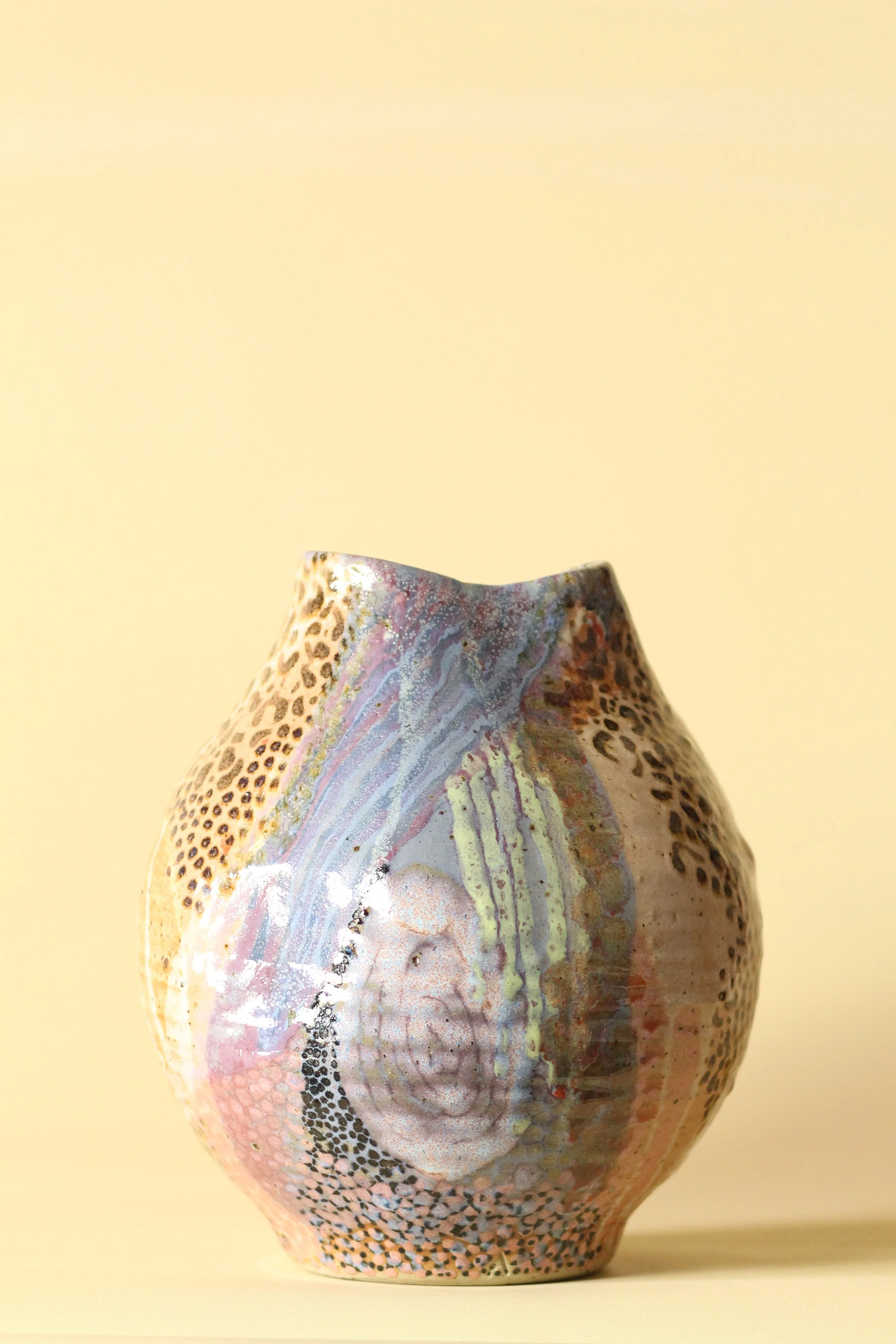 Decorative vase with multicolored marble and animal print pattern against a beige background.