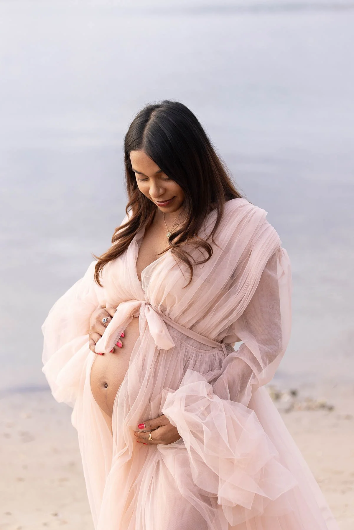 Pregnant woman in pink dress in the water at sunset North Shore Maternity photographer