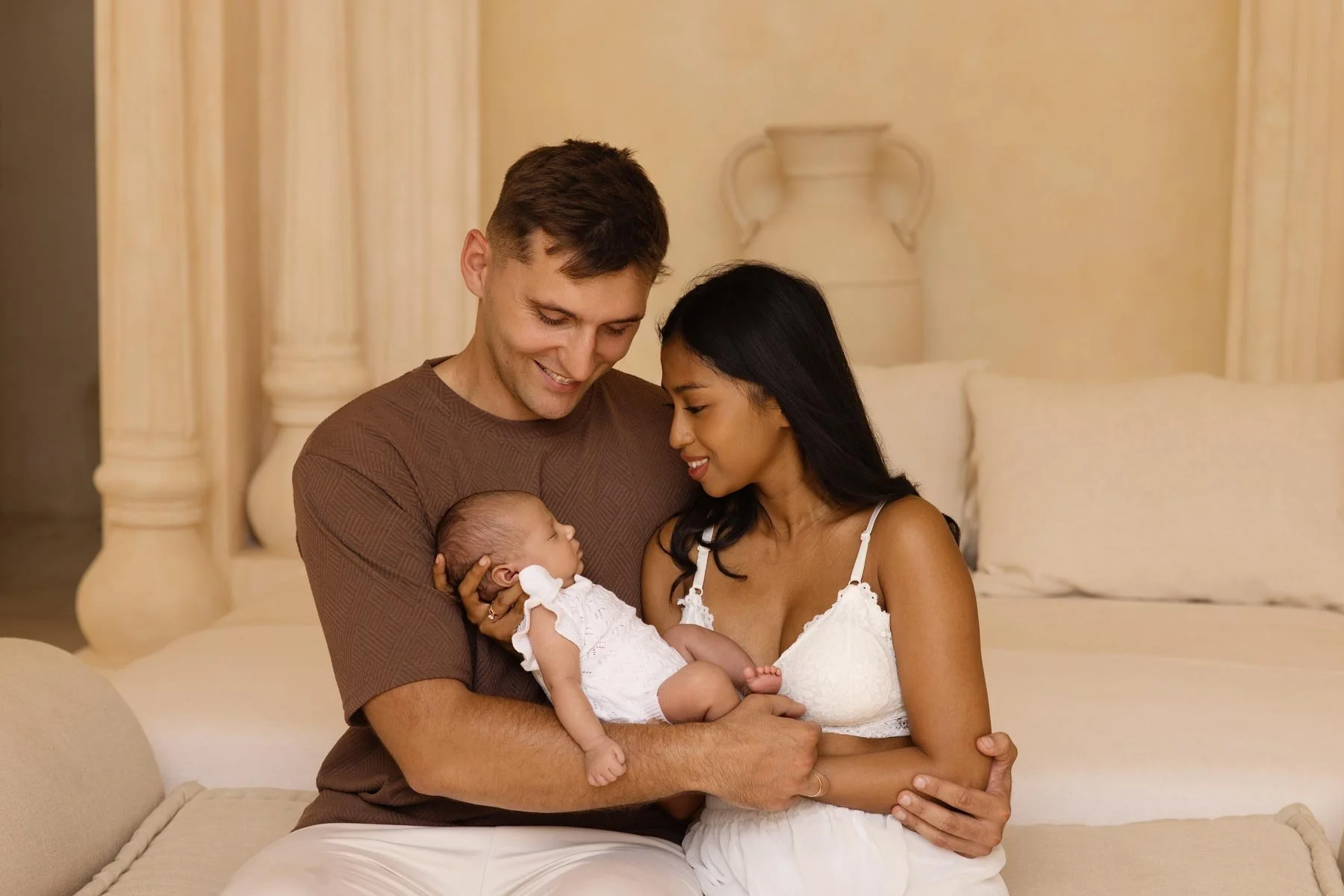 couple holding their newborn baby at home in a beautiful boho decor
