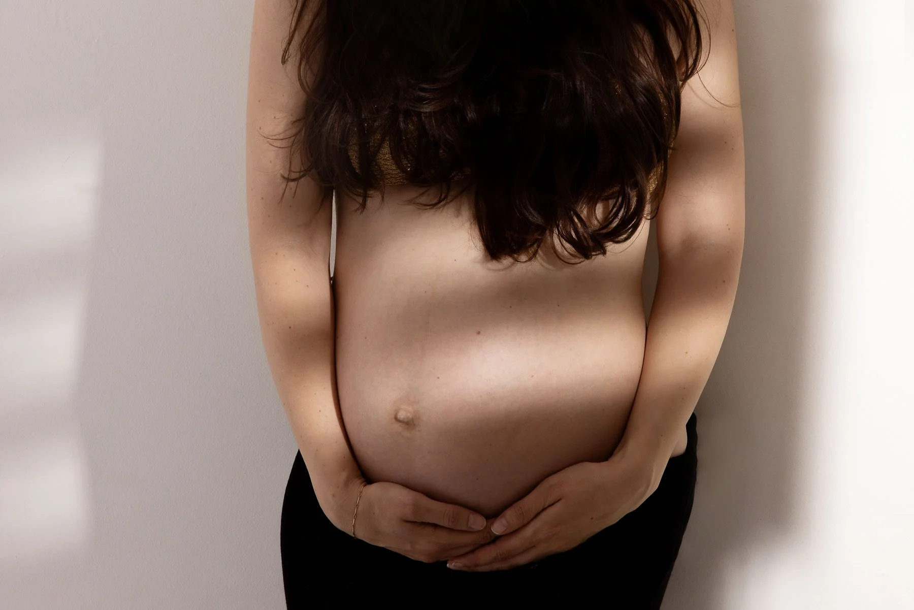 Pregnant woman holding belly, wearing black skirt