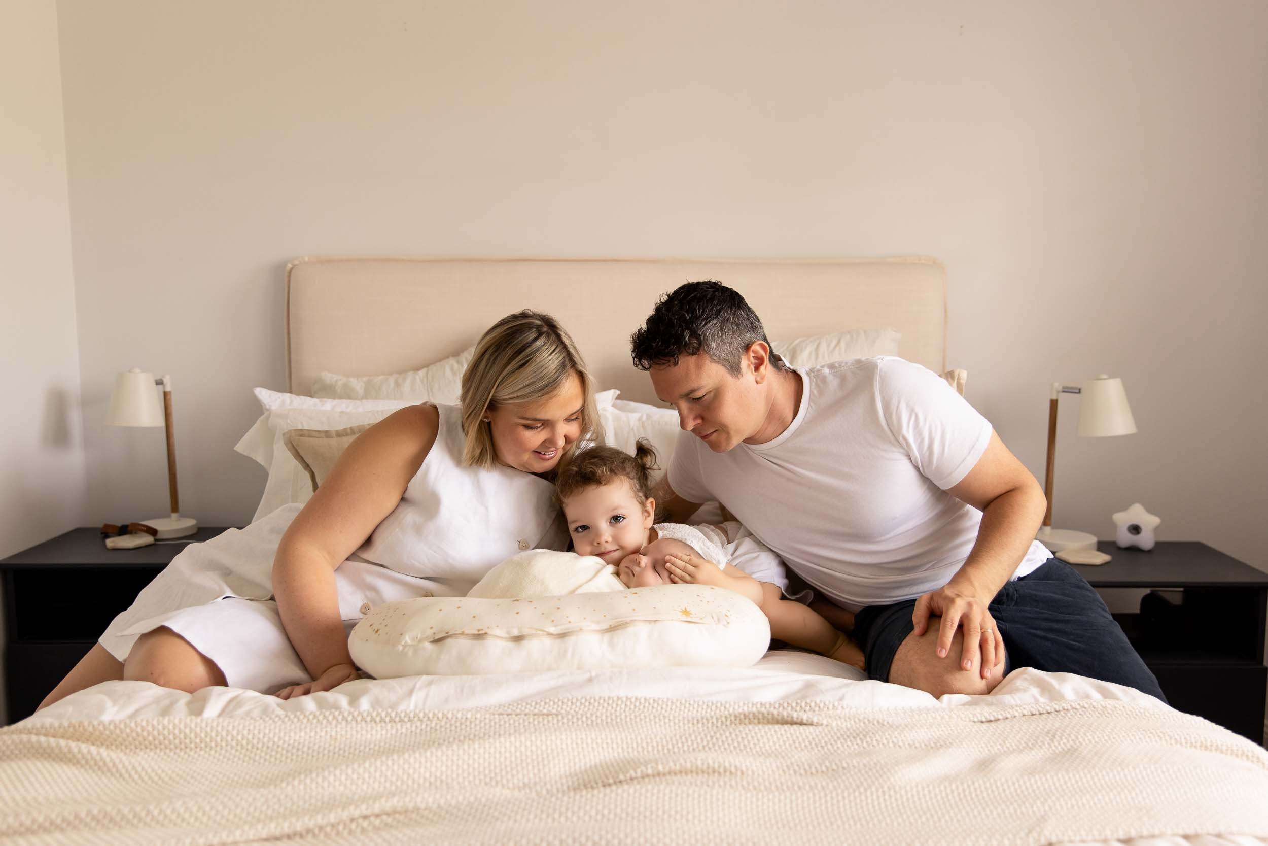 Family with child sitting on bed in cozy bedroom.
