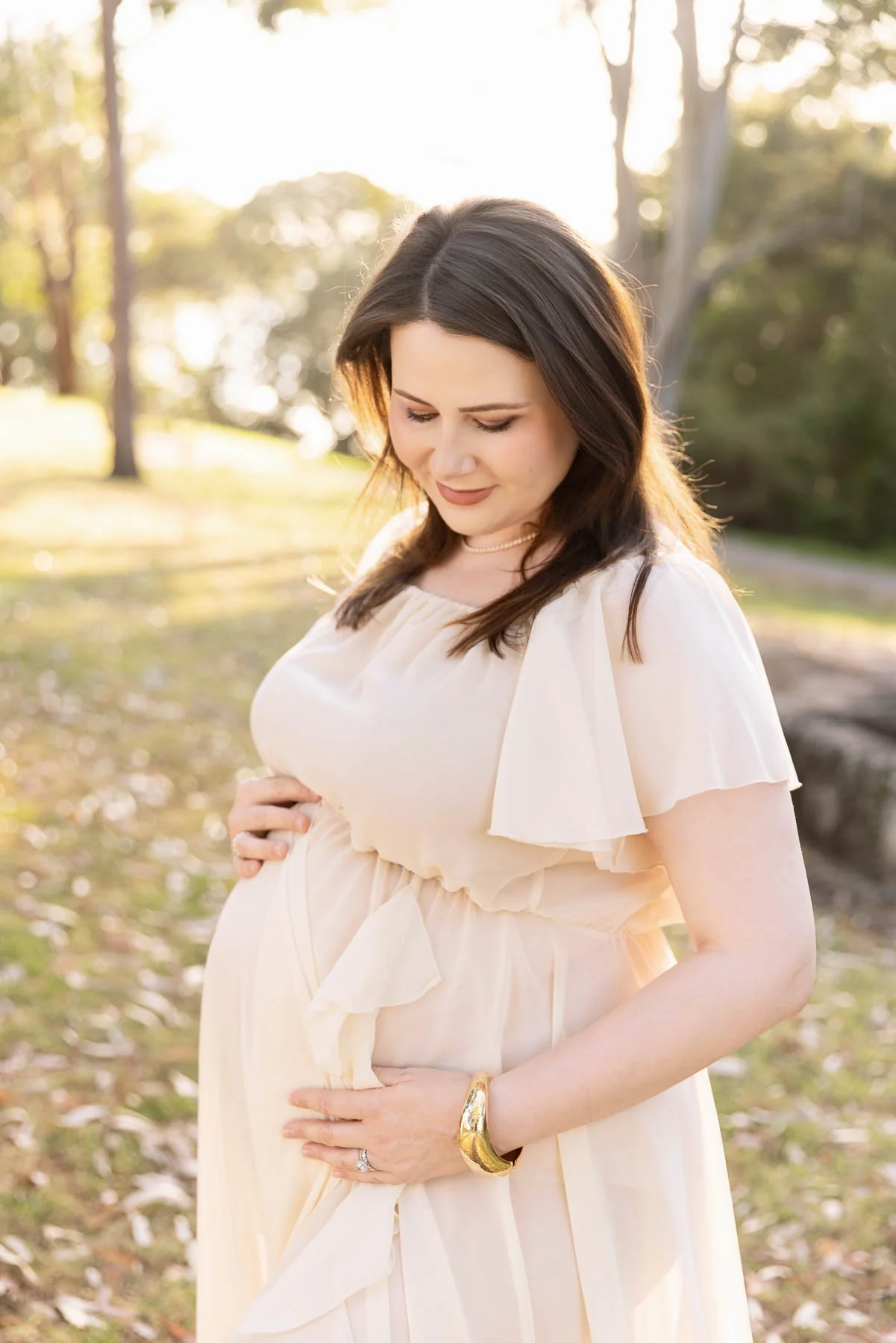 Pregnant woman in off white dress in the forest at sunset North Shore Maternity photographer