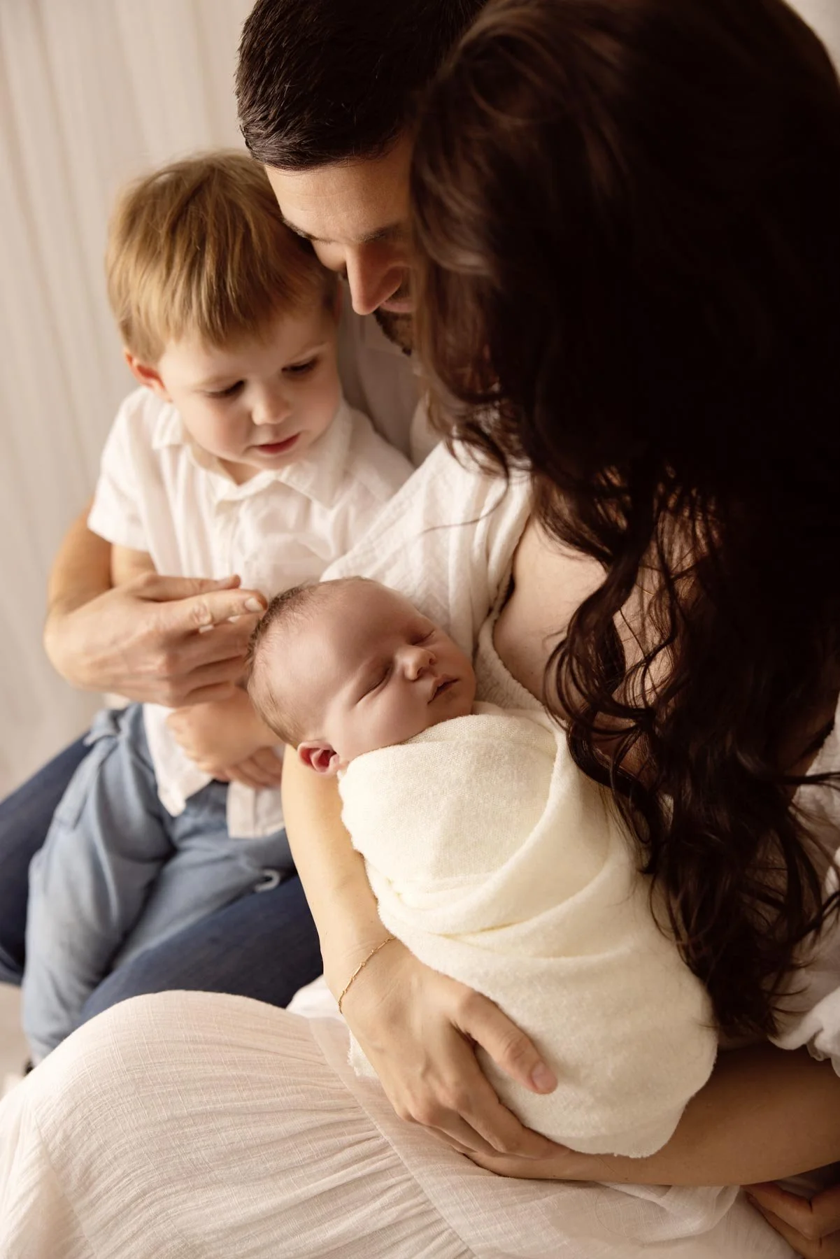 family portrait with a toddler looking at a newborn baby