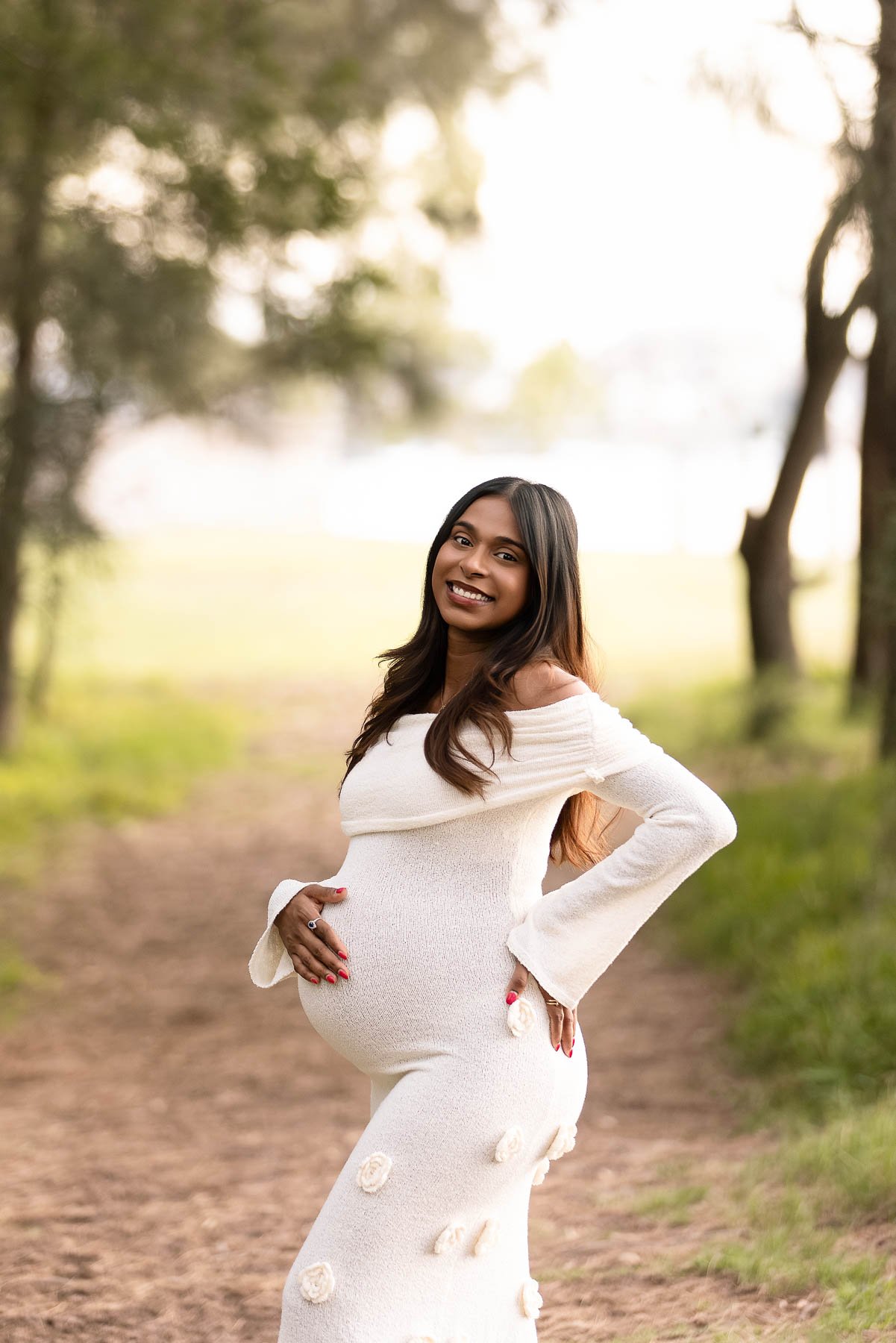 Pregnant woman in white dress near the water at sunset North Shore Maternity photographer