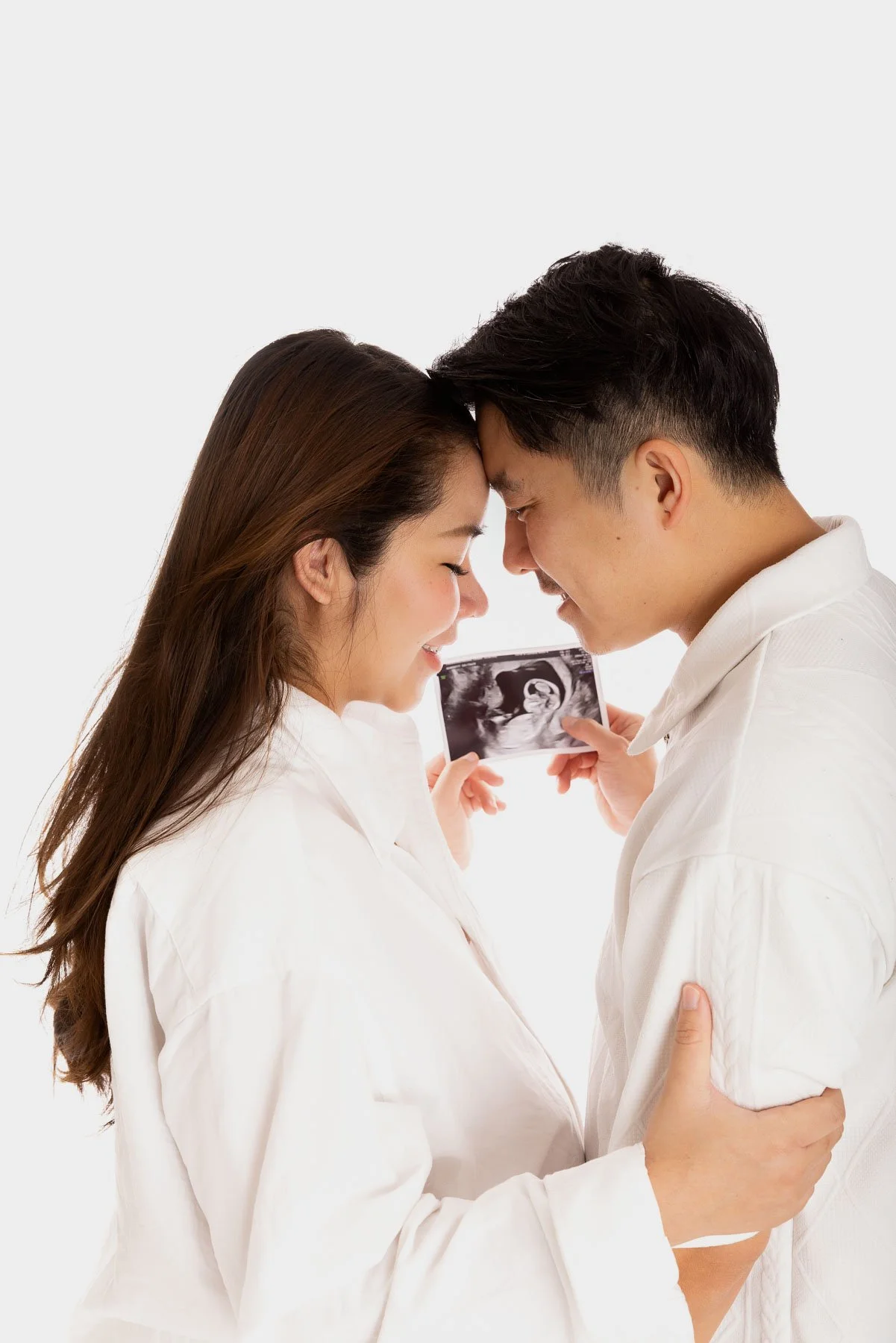 Black and white silhouette of a pregnant woman and her husband holding the ultrasound photo