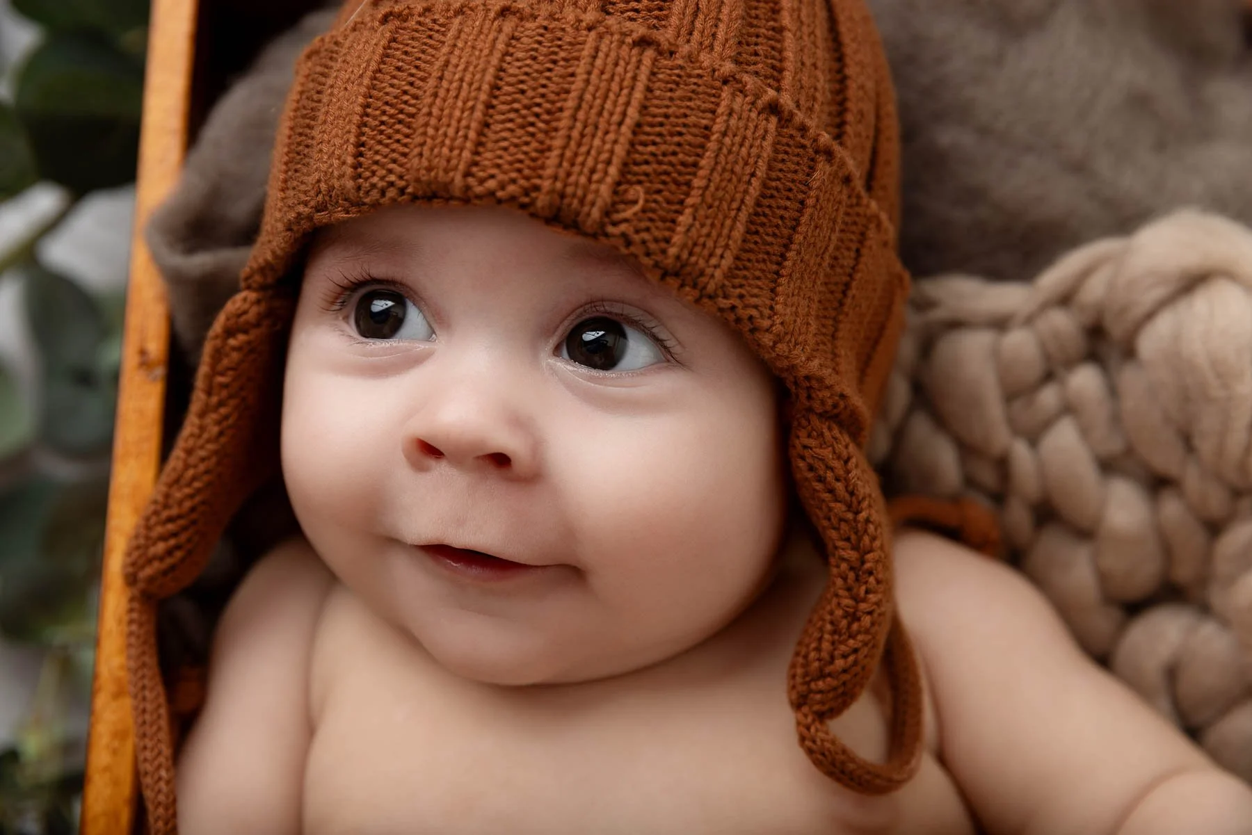 Baby wearing a brown knit hat, looking upwards.