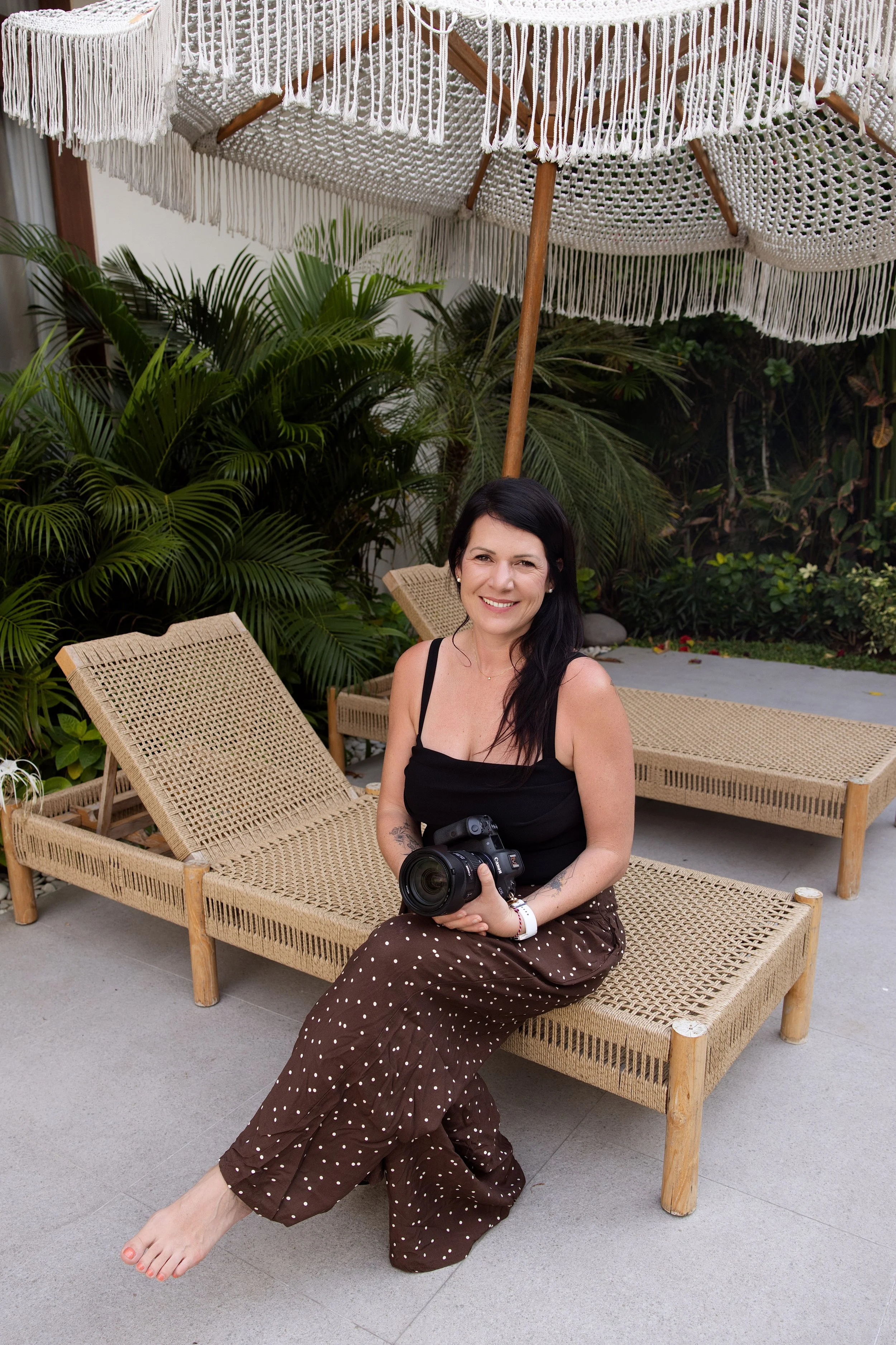 Portrait of Noemie Vonthron holding her camera and smiling sitting on a longchair