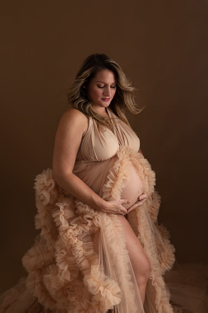 Pregnant woman in flowing gown holding her belly