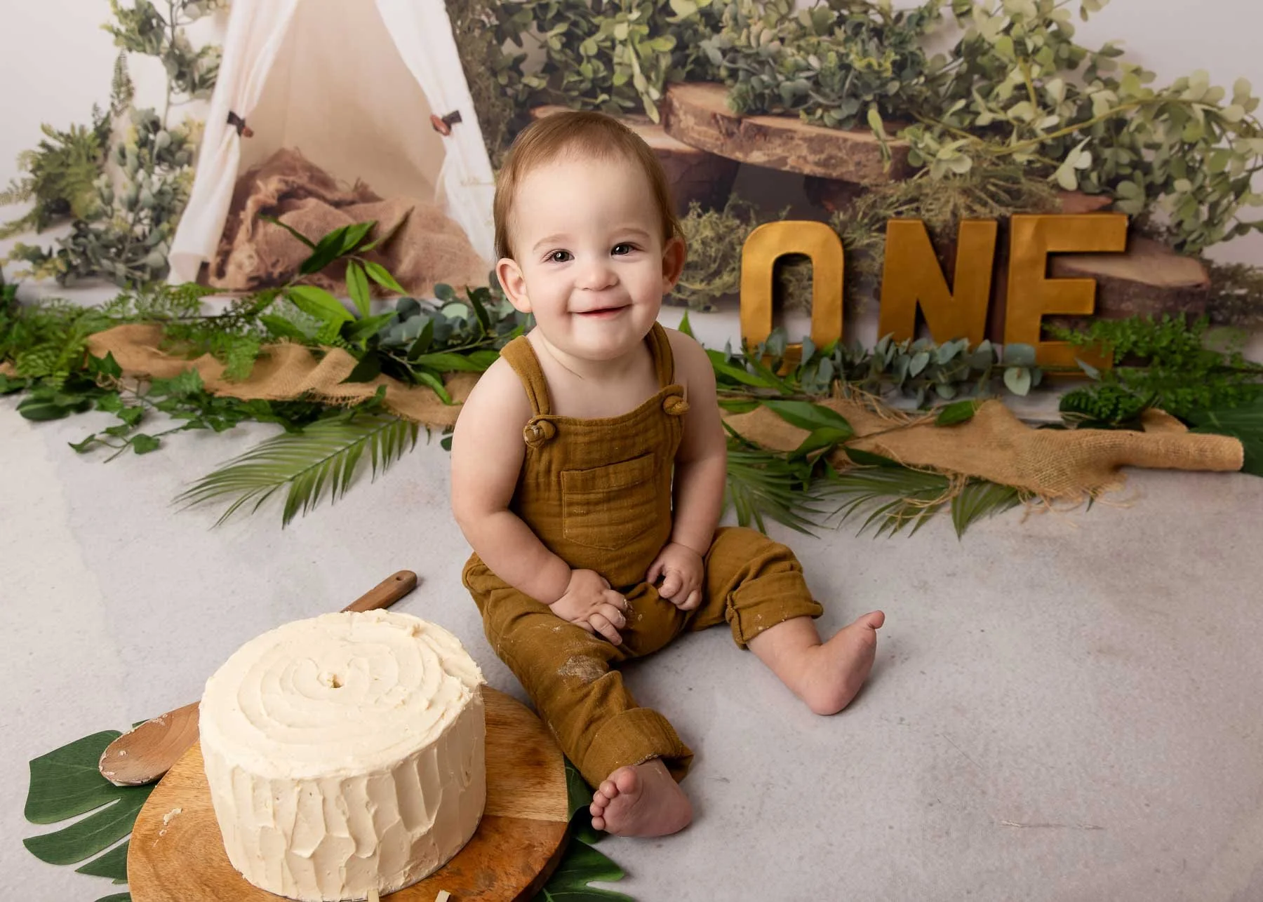 Cake smash photographer Sydney North Shore baby sitting up and smiling in front of a birthday cake