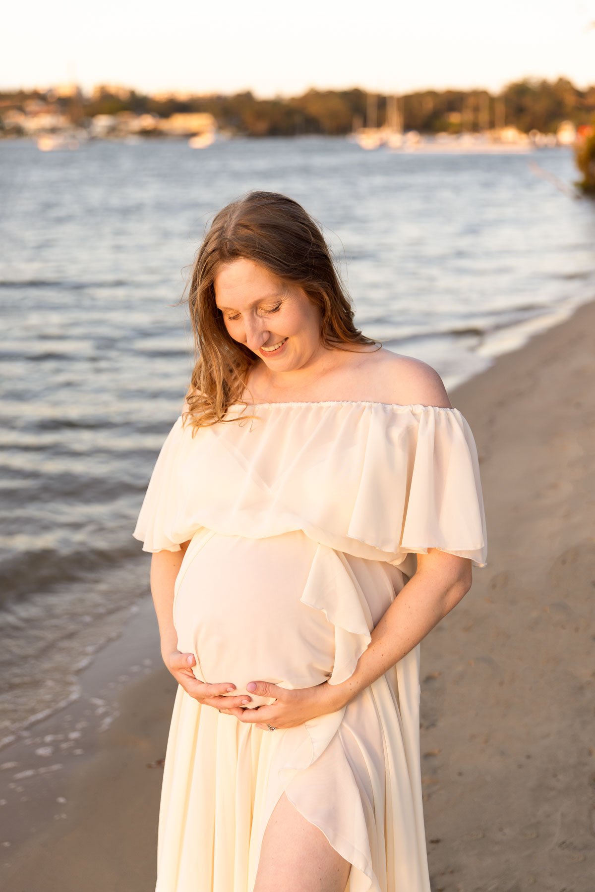 Pregnant woman in white dress in the water at sunset North Shore Maternity photographer