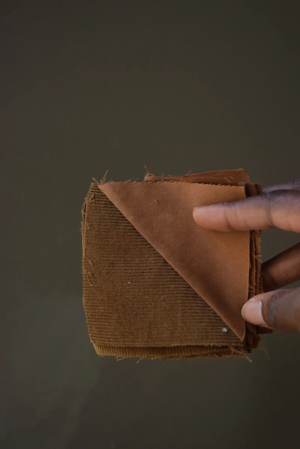 Carré bicolore d'un pantalon en coton camel et d'une chute de tissu en velours côtelé marron.