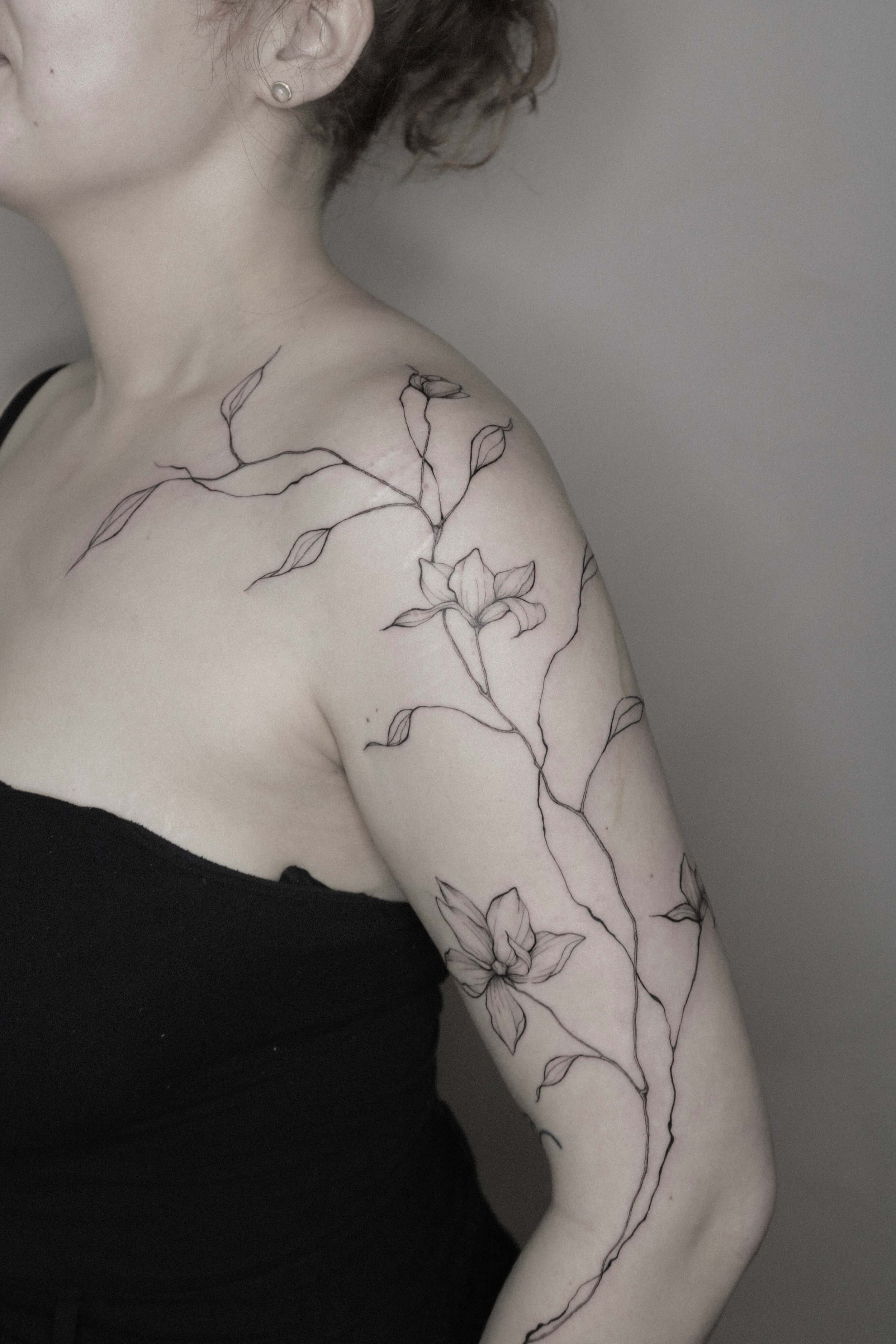 Frau mit floralen Tattoos auf Schulter und Arm